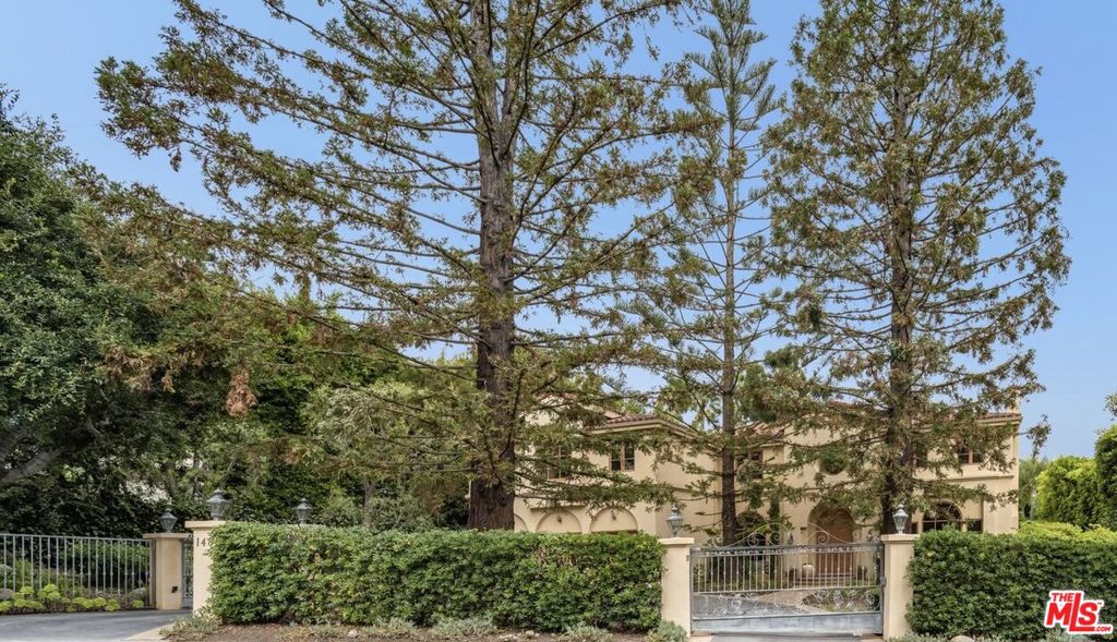 Nestled in the heart of the prestigious Riviera Palisades, this Estate behind gates showcases immaculate scale and quality design. Passing through the grand formal entryway, you are greeted with a sweeping staircase, high ceilings with classic wooden beams and ample natural light flooding in from the formal living space, complete with a fireplace. Across the entry, the family room features custom floor-to-ceiling built-ins and stunning coffered ceilings, allowing for the perfect intimate space to entertain guests. The classic formal dining room with vaulted ceilings is perfectly situated next to the oversized outdoor patio with a covered veranda wrapped in lush green vines, providing a peaceful yet multi-functional dining and entertaining space. In addition, the large kitchen and breakfast area are accompanied by an informal secondary family room with fireplace, bar, and wooden beams on the ceiling, providing a feel of immense warmth and comfort. Upstairs, a long sun-filled hallway with custom built-ins leads to the primary suite, featuring a fireplace, large balcony overlooking your private backyard oasis, and large bathroom with dual closets. There are three additional bedrooms with en-suite baths followed by a bonus room, bringing forth endless opportunities for whatever your needs are. Outdoors, the backyard oasis with pool and spa boasts tall trees surrounding the entire yard, creating privacy and serenity. This property is an opportunity not to be missed.