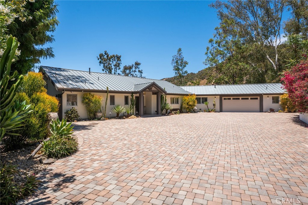 Welcome to this exquisite one-story retreat nestled behind private gates in the picturesque hills of Calabasas. Thoughtfully remodeled, this five-bedroom, four-and-a-half-bath sanctuary offers refined living in a stunning mountain setting. Step inside to discover a spacious, light-filled open floor plan accented by soaring ceilings and designer finishes throughout. The gourmet chef’s kitchen is the heart of the home, boasting an oversized island ideal for entertaining, high-end appliances, and seamless flow to the dining area and expansive great room. Enjoy cozy evenings by the elegant fireplace, surrounded by custom built-ins, or open the doors to experience true indoor-outdoor living with uninterrupted mountain vistas.The spectacular primary suite is a true retreat, featuring its own fireplace and a completely reimagined spa-inspired bathroom with a large walk-in closet. On the opposite side of the home, a private wing hosts three additional bedrooms and two full bathrooms — perfect for family or guests. The separate fifth bedroom offers incredible versatility, complete with its own bathroom and private patio — ideal for a home office, guest suite, or potential ADU. Step out onto the expansive balcony directly off the kitchen and great room, designed for unforgettable gatherings under the stars. Complete with an outdoor bar, inviting Jacuzzi, and ample space for large alfresco dinners, this backyard is an entertainer’s dream. Meander down the charming garden path to discover lush gardens and a dedicated garden enclosure— a paradise for any gardening enthusiast. Combining serene natural beauty, thoughtful design, and exceptional amenities, this stunning property offers a rare opportunity to live the quintessential Calabasas lifestyle. Whether hosting summer soirées, enjoying peaceful mornings with mountain views, or relaxing in your private retreat, this home truly has it all.