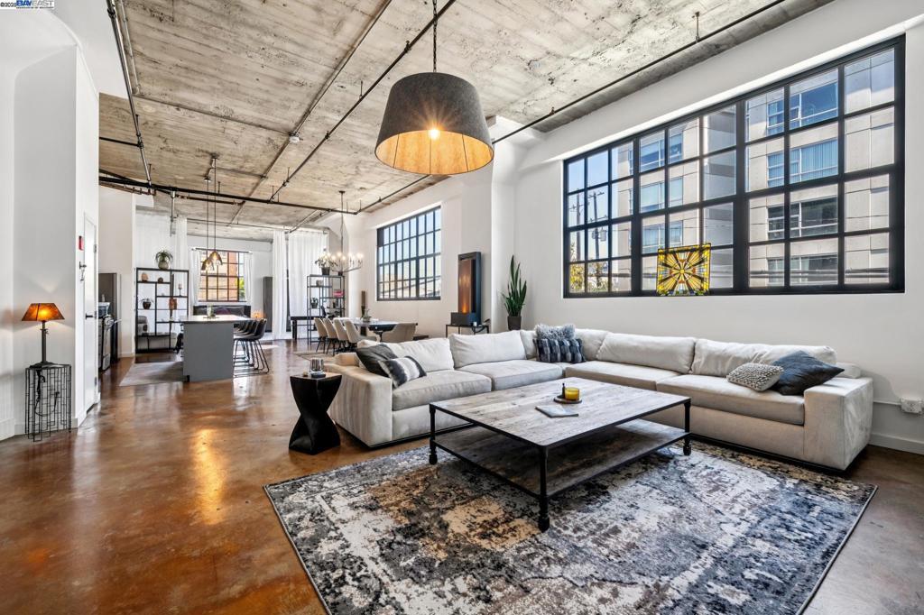 With a rich history, this nearly 2000 sqft. industrial loft provides a brilliant canvas to create your own amazing story. Formerly Safeway’s 1920’s corporate warehouse this rare property houses the original walk-in corporate safe… but save your money elsewhere and enjoy the striking chandelier suspended in your bedroom, office or library. Rugged industrial chic has never felt so fresh with oversized black enamel pendants, chandeliers, and crisp white walls. The towering concrete ceilings, pillars, and steel framed windows suggest the historical story, while the modern updates suggest you can absolutely have it all. The floorplan is effortless, the space, simply enormous. The kitchen is simple, practical, anchored by a large island where your friends are sure to gather. Up the stairs find your secret hideaway, an open loft might be the perfect playground for media, hobbies, or a Zenful retreat. Two large closets give ample storage, or perhaps some coats and a near perfect walk-in wine cellar. In-unit laundry with secured two-car parking and a large basement storage closet sweeten the deal. Fourth Street Lofts is an exciting community in the fabulous Jack London Square neighborhood. Originally a 1923 Safeway Corporate warehouse, this complex’s rich history feels iconic.