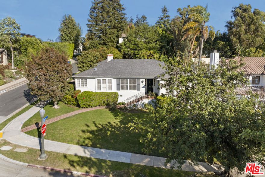 Set on a gentle knoll in Prime Westwood Hills, this very charming Traditional home is sited on a comparatively larger, maturely wooded parcel on the prestigious corner of Bentley and Denslow Avenues. Built in 1939, its period architectural elements are well-preserved and gleaming...wainscoting, crown moldings, rich, wood paneling, hardwood flooring and French windows and doors. The center-hall floor-plan is sensible, emanating from a formal foyer. The living room, with its bay window and beautiful fireplace is bright and sunny. The formal dining room is as well. The kitchen features quality appliances and is adjacent to a flexible space serving easily as an informal family room. The three bedrooms are all amply sized. There's also a very warm and cozy den with another fireplace. This space does have the potential to be converted to a fourth bedroom if desired. A powder room and a separate laundry room complete the floorplan. The expansive backyard is serene and sunny complete with lovely patio and a grassy area. Central Air and Heat. Security system. All this in close proximity to UCLA, Westwood, Brentwood, Century City and Beverly Hills and all the fine shopping and dining each area affords. Highly sought after inclusion in the Warner Avenue Elementary School District.