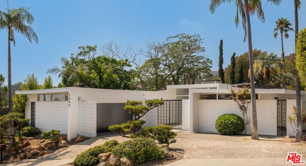 Nestled on one of Bel Air's most prestigious streets, this meticulously restored mid-century masterpiece epitomizes sophisticated California living. Set on an expansive three-quarter-acre west-facing lot, the single-story residence seamlessly marries breathtaking canyon views with an effortless indoor-outdoor lifestyle. The home has been thoughtfully reimagined for contemporary living while preserving its authentic mid-century soul. Original brass-bordered terrazzo floors and rich herringbone hardwood create a foundation of timeless elegance, while expansive walls of glass bathe the interiors in natural light and frame serene canyon vistas. A dramatic skylight adds another layer of illumination, and the iconic round black terrazzo fireplace serves as a striking focal point that anchors the living space. Spanning approximately 3,100 square feet, the residence offers four bedrooms and three-and-a-half bathrooms, complemented by thoughtful entertaining spaces. The spacious primary suite features a walk-in closet and a luxurious bathroom with a steam shower, creating a true spa-like retreat. The dining area includes a sleek wet bar perfect for hosting, while the family room showcases custom built-in cabinetry that seamlessly blends form and function. A dedicated game room and spacious mudroom/laundry complete the interior layout. The outdoor spaces are equally impressive, featuring a resort-style pool and spa, professional BBQ area, and expansive flat grassy yard - all designed for both intimate gatherings and grand-scale entertaining. A two-car garage with direct access and a circular motor court with ample parking. This is a rare, turnkey offering in prime Bel Air - an architectural gem where classic mid-century design meets modern luxury in a truly exceptional canyon setting.
