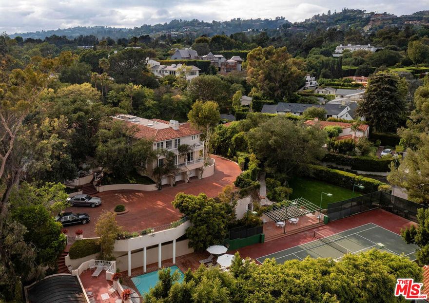 Architectural pedigree meets Old Hollywood. Once in a generation & rare opportunity to own an iconic estate steeped in entertainment history. The Fries Estate, once owned by Paramount Pictures, is an incredible promontory compound on appx. 1.2 acres w/ a legendary pool house designed by Paul Williams. Features: long gated driveway w/ massive motor court, main home has ideal floor plan w/ grand scaled public rms, primary w/ sitting rm, dual walk-ins, frplc + 2 en-suite bdrms up. 2 staff on main level. Lower level w/ huge theater, game rm, wine cellar, gym, staff rm & 2nd kitch. Your own personal Beverly Hills Hotel experience awaits. Enjoy days at the pool & pool house, create your own private Polo Lounge in the brick courtyard w/ fountain & enjoy walks in the park-like grounds & tennis in the N/S court w/ pavilion. Verdant landscape & mature trees envelope the home in privacy & create a magical backdrop for living/entertaining in style. The essence of quintessential Beverly Hills.