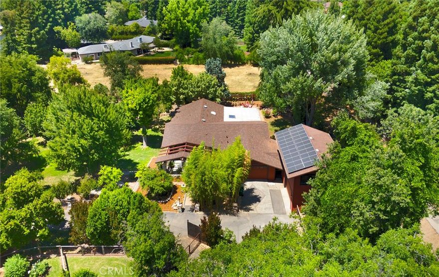 Incredible opportunity to own this quiet west side 3br/3ba home with a 1br/1ba apartment!  Tucked away at the end of a peaceful cul-de-sac on just over an acre, this incredible and unique property offers a serene retreat surrounded by a family orchard with a variety of fruit trees and a breathtaking collection of Japanese maple trees.  A custom-designed Japanese-style garden and koi pond—proudly featured on the Chico Pond Tour for years—add to the property’s tranquil charm. The main home features three spacious bedrooms, each with its own en-suite bathroom, and two distinct living spaces. Fresh interior paint brightens the home throughout. The front living room is filled with natural light from large windows, while the heart of the home—the family and dining area—boasts stunning open-beamed vaulted ceilings, wide 5/8” scraped maple flooring, and French doors that lead to a covered patio. The kitchen is beautifully designed with custom cabinetry, granite countertops, a central island with built-in wine rack and bookcase, a commercial-grade 6-burner Blue Star range, and a walk-in pantry. The luxurious primary suite offers coffered ceilings, a large 3-door closet and a walk-in closet, and a beautifully remodeled en-suite bath with dual sinks on a custom walnut countertop and a spa-like steam shower featuring multiple rain heads and a waterfall. Additional features in the main home include owned solar, a brand new roof, an oversized 2-car garage, a whole house water softener, a whole house fan, and two HVAC units for efficient climate control. Beyond the main house, the property includes an additional 2-car garage with an attached workshop and a full apartment above. The apartment offers its own HVAC unit, water heater, full kitchen, and generous living space—perfect for guests, extended family and has been an excellent source of rental income for the current owner.  This truly special property blends nature, privacy, and great updates into one unforgettable home. Come experience it in person!