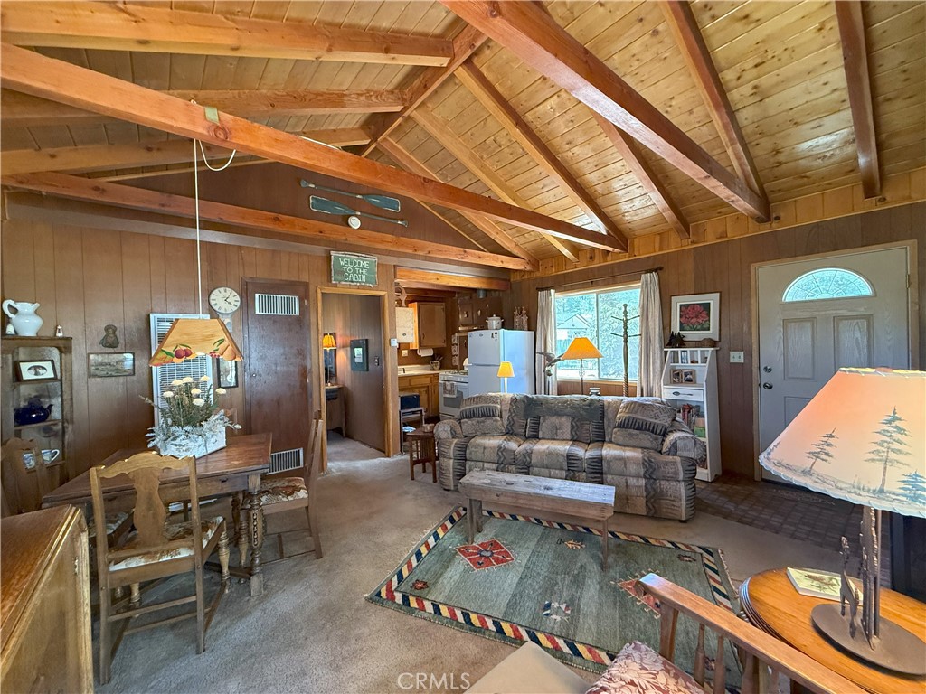 Escape to this storybook cabin tucked away in the scenic beauty of Big Bear City. This 1-bedroom, 1-bathroom furnished retreat offers 504 square feet of charm and comfort, perfect as a weekend getaway or peaceful year-round hideaway. Inside, the spacious family room steals the show with its exposed wood beams, vaulted ceilings, and a welcoming fireplace that invites you to cozy up on chilly mountain evenings. Step outside to a generous 6,750 square foot level lot—offering endless potential. Whether you're dreaming of adding a garage, expanding the living space, or creating the ultimate outdoor hangout, the possibilities are yours. Enjoy recent upgrades including a brand-new roof, fresh exterior paint, and a new gravel driveway. Surrounded by the natural beauty of the mountains, this cabin offers the perfect place to enjoy all four seasons—whether it's snow in the winter or sunshine-filled summer adventures on the lake or hiking and off-roading on the surrounding mountain trails. Located in a peaceful Big Bear City neighborhood, just minutes from the lake, hiking, and ski resorts, this cabin is a rare find with plenty of room to make it your own.