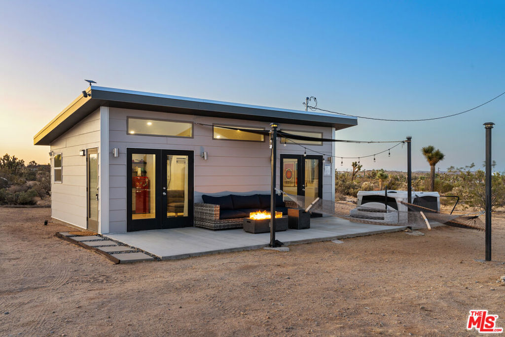 Welcome to Desert Rose - a design-forward micro cabin nestled on 5 serene acres atop the mesa of Yucca Valley. This mid-century-inspired bungalow offers the perfect blend of charm, privacy, and potential - ideal as a personal escape, a successful short-term rental, or the foundation for future development. Inside, you'll find wide-plank floors, an open-concept layout, and sun-filled interiors that feel both cozy and spacious. Thoughtful touches throughout create a peaceful, modern desert aesthetic that connects effortlessly with the surrounding landscape. Outside, unwind under the stars in your private hot tub, sway gently in hammocks amongst the Joshua Trees and let the soft glow of bistro lights set the mood for slow, dreamy evenings. With 5 acres of flat, buildable land, there's room to add structures, create a compound, or subdivide - all while enjoying uninterrupted views and total seclusion. Currently a highly rated Airbnb, this property offers a turn-key investment opportunity with a proven track record of guest satisfaction and income potential. Whether you're seeking simplicity, inspiration, or income, this petite hideaway is a rare and beautiful opportunity in the heart of the High Desert.