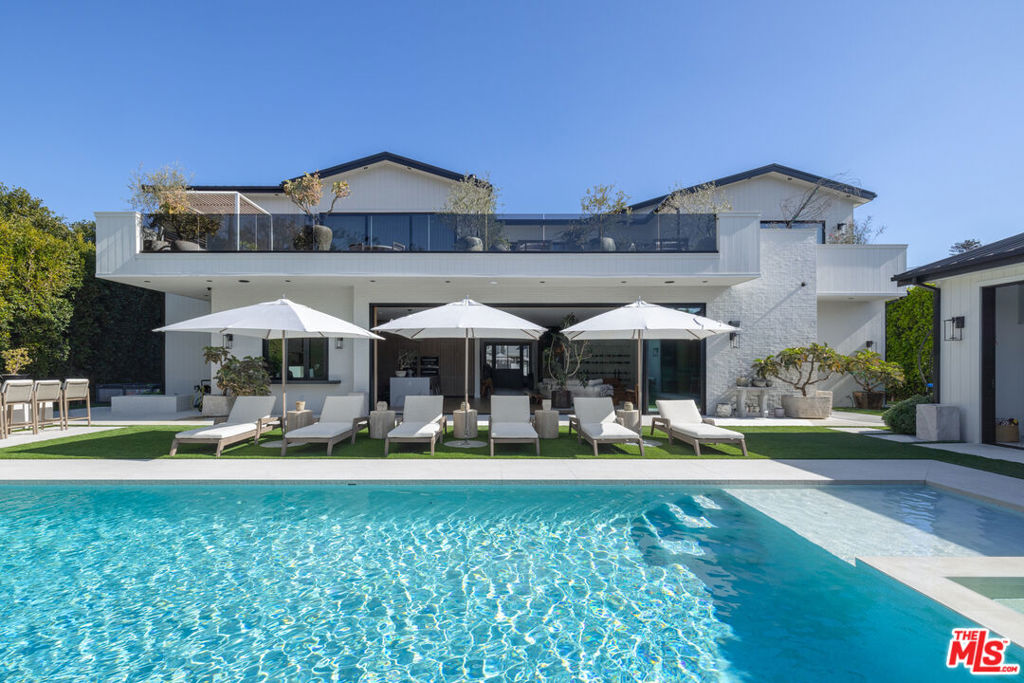 Tucked behind custom gates and mature hedging on one of the widest lots in the flats of North Bundy - with 120 feet of frontage - this modern Brentwood estate delivers an extraordinary blend of privacy, design, and innovation. The main residence offers 5 bedrooms and 7 bathrooms, plus a versatile office/den/nursery, while a fully equipped detached guest house with its own bedroom and bathroom brings the total to 6 beds and 8 baths. Purposefully designed for both entertaining and daily comfort, the home opens to a resort - style backyard with a large, private pool, mature landscaping, an outdoor kitchen, and a fire pit - your own secluded sanctuary. The expansive lot also offers space to add a sports court on the side of the home. A spacious 2-car garage is complemented by gated parking for up to four additional vehicles. Security is next-level, featuring an AI-powered camera system, automated perimeter alerts after hours, and 24/7 armed patrol service already in place - ensuring peace of mind without compromise. Inside, expansive open-plan living spaces connect effortlessly to the outdoors. The main kitchen stuns with dual islands, all Miele built-in appliances - including an espresso station, refrigerator, oven, microwave, and dual dishwashers - and a sleek frameless integrated stovetop. Discreetly tucked away, the chef's kitchen is ideal for hosting or staff use, outfitted with an 8-burner Wolf range, additional Miele refrigerator and freezer, and a spacious walk-in pantry. A climate-controlled wine rack adds sophistication and function for wine collectors. For elevated living and entertaining, the home includes a state-of-the-art private theater with over $100K in hidden, professional-grade AV equipment and acoustically transparent finishes - creating a truly immersive cinematic experience. Upstairs, a sun-drenched hallway opens to a spacious deck for second-level indoor-outdoor living. The primary suite features its own private terrace with fireplace and a walk-in closet, complete with custom cabinets and island with key-card access drawers for valuables. Three additional guest bedrooms upstairs each offer en-suite baths and custom closets- ideal for balanced family living. Smart home integration elevates every detail, with wall-mounted displays and app-based controls for lighting, climate, sound, and security. A roof-mounted cell antenna boosts signal, and Wi-Fi boosters ensure strong, consistent coverage throughout the property. Custom furniture and collectible lighting fixtures - meticulously curated to complement the home's design - are also available for purchase.