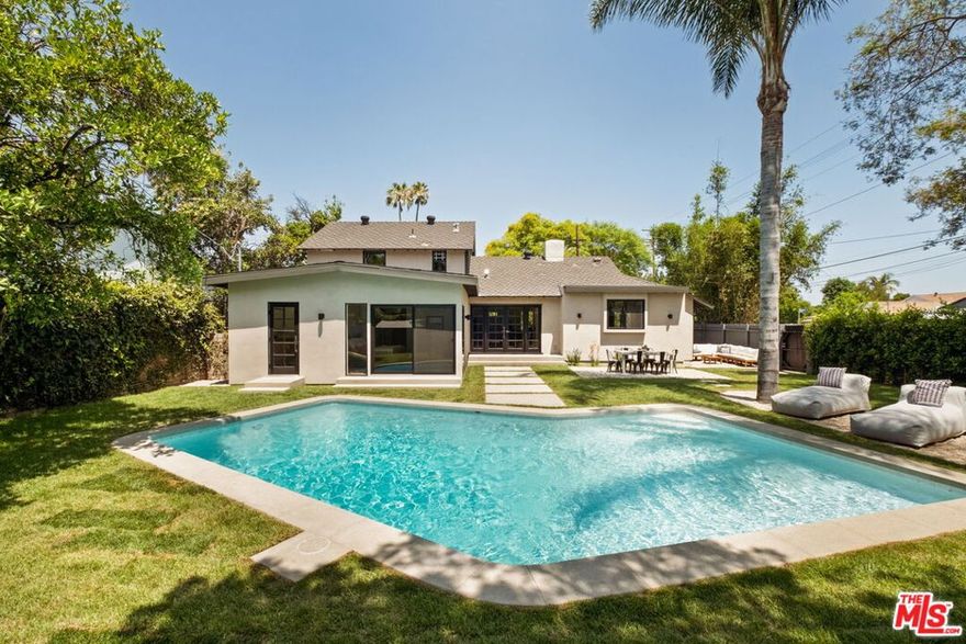 Welcome to this exquisite, renovated mid-century home, nestled in the heart of the valley. From the moment you arrive, you'll be captivated by the home's timeless elegance and stylish design. Featuring four generous bedrooms and three meticulously upgraded bathrooms, this property sits on an expansive lot complete with a large pool and a spacious backyard with two large palm trees at the end of the pool. Inside the living room you are welcomed by abundant natural light, high exposed beam ceilings, and a striking fireplace that creates a warm and welcoming atmosphere. The adjacent dining area features diamond lattice windows that add a touch of charm and character. At the heart of the home lies a spacious chef's kitchen designed for both function and style. It boasts elegant marble countertops, custom cabinetry, a convenient breakfast bar, a premium Viking stove, and a beautifully integrated Dacor built-in refrigerator and freezer. French doors lead directly from the kitchen to the stunning backyard and pool. Down the hall, you'll find a  guest bedroom and a luxurious primary suite. The primary offers a generous bedroom area, a massive walk-in closet, and a spa-like ensuite bathroom complete with double sinks, a large walk-in shower, and sleek porcelain countertops atop custom cabinetry. Upstairs you'll find two more bedrooms and a large bathroom thoughtfully laid out so the kids have a quiet place to relax while the adults continue outside near the pool on long summer nights. The expansive backyard boasts a spacious pool, ample room for entertaining, mature trees and ficus hedges for added privacy, and two towering palm trees that capture the quintessential California style. This property provides easy access to Sherman Oaks, Burbank, Encino, Studio City and more. It's just 10 minutes from the Sherman Oaks Whole Foods and Ventura Blvd. It is a special, quiet retreat that captures the very best of life in the San Fernando Valley.