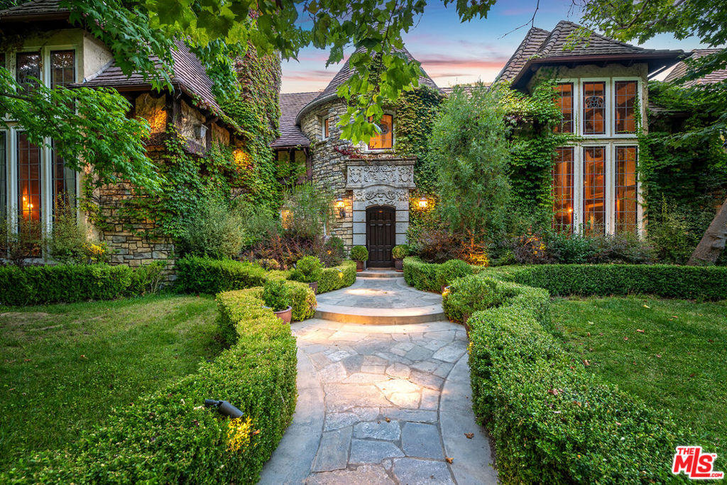 Behind the gates of the exclusive guard-gated Moraga Estates in Bel Air, this extraordinary 6-bedroom Traditional "storybook-style" estate blends European charm with California luxury on an approximately 83,328 sq.ft. lot, or just under 2 acres. The main house spans over 9,500 sq.ft. and is a true showcase of architectural beauty and refined living. Nestled on a sprawling lot with mature vines of Cabernet Sauvignon and Sauvignon Blanc, the property offers a rare combination of elegance, enchantment, and serenity. The main level of the home features a beautiful formal living room with fireplace, a built-in bar, and a magnificent library fit for royalty, fully clad in rich wood paneling with built-ins, coffered ceilings, and a grand fireplace. A spacious family room with fireplace, a grand foyer with a stunning spiral staircase, and a formal dining room adorned with two-story leaded and stained-glass windows fill the home with warmth and light. The expansive gourmet kitchen includes a long eat-in center island, professional-grade appliances, and a sunny breakfast room that opens directly to the central courtyard with a fountain and an outdoor kitchen complete with built-in barbecue and generous island seating. The architectural details evoke timeless romance - arched doorways, steep pitched roofs, and ivy-draped stonework - creating a home that feels both majestic and magical. The beautifully landscaped grounds are lush with mature trees and greenery that provide both shade and privacy. A full-size tennis court includes a viewing pavilion above, perfect for entertaining. The massive primary suite is a luxurious retreat, offering a fireplace, large private balcony overlooking the pool and gardens, dual custom walk-in closets, and a spa-quality marble bath with steam shower, sauna, separate soaking tub, multiple vanities, and even a barber's chair. Additional features include an attached 3-car garage and approximately 4,500 sq.ft. of bonus space with endless possibilities for a screening room, game parlor, gym, or creative studio. The property also offers a pool, spa, koi pond, formal garden, and a custom wine cellar carved into the hillside. Offered fully furnished for a seamless move-in or investment opportunity, this magical estate is tucked away in one of Bel Air's only 24/7 guard-gated communities - just minutes from Brentwood, Beverly Hills, and top-tier schools. A rare opportunity to own a legacy estate that offers scale, serenity, and timeless elegance.