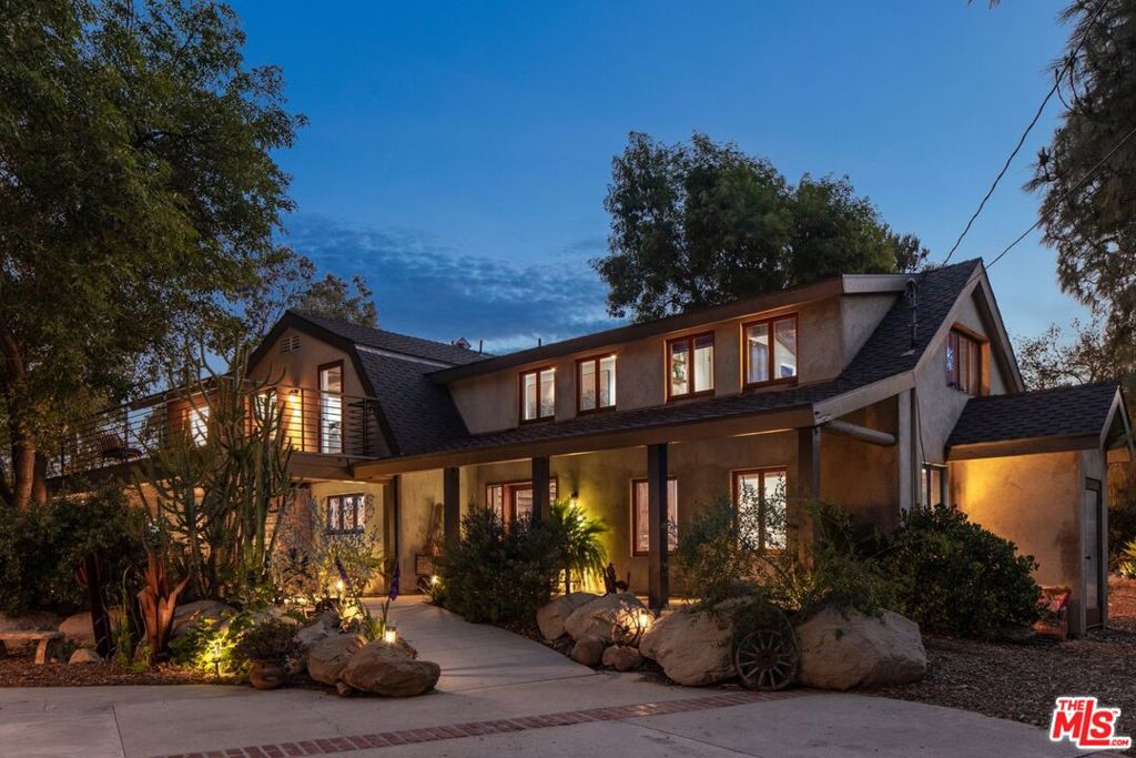 Perched on over eight private acres, this one-of-a-kind estate is framed by massive sandstone boulders, mature trees, secret pathways, and sweeping views of the San Fernando Valley. A long private driveway leads to the residence, passing tranquil water features and scenic observation points that lend the property a park-like serenity while the natural rock formations offer complete privacy. The two-story residence features clean lines, wrap-around patios, and custom floor-to-ceiling wood and glass doors that flood the home with natural light. Inside, restored antique wood floors, exposed beams, and reclaimed barn wood details add warmth and character. The remodeled chef's kitchen is outfitted with Viking and Fisher & Paykel appliances, built-in storage, and sliding drawers. Each bedroom is a private retreat. The primary suite occupies its own wing, with a fireplace, walls of glass, and an artisan bathroom featuring a clawfoot tub. Upstairs, an A-frame ensuite overlooks the boulder formations, while a sunlit office and lounge open to expansive decks. Equestrian amenities include sand-filled corrals, run-in sheds, a wash rack, and tack rooms. The adjoining 5-acre lot offers 3 prime build sites for future expansion or recreation (see last photo). Beyond the residence, lush gardens, natural rock waterfalls, hidden pathways, and private trails complete this exceptional offering. Raised vegetable and cactus gardens, two custom-designed water fountains, and extensive solar lighting create a magical landscape. Additional features include a storage basement, tree-watering system, 500-gallon backup water tank, and wall-mounted EV charger. An extra large garage has been converted to a work or living area - perfect for a home studio. 7336 Studio Road stands as a singular statement of architectural elegance and natural beauty delivering an unparalleled lifestyle defined by privacy, serenity, and enduring design. Property to be sold with Adjacent land, APN: 648-0-210-140 (Included in listed Lot Sqft)