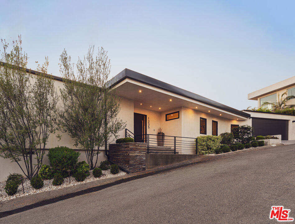 Tucked away in the hills of Kenter Canyon, this single-story modern compound in the exclusive Crestwood Estates exudes effortless California cool. Reimagined with sleek design, sophisticated finishes, and a seamless indoor-outdoor flow, it's the ultimate private retreat for elevated living. Step inside and feel the calm as a wide-open floor plan framed by walls of glass dissolves into lush treetops and canyon views that stretch all the way to the ocean. The living room stuns with a sculptural fireplace, custom built-ins, and moody ambient lighting that sets the tone. At the heart of the home, a dedicated dining area flows into a showpiece chef's kitchen anchored by a massive island perfect for cooking, entertaining, or late-night conversations. Warm wood-beamed ceilings, double prep stations, Viking appliances, a wine fridge, and tailored cabinetry give the space a vibe that's both organic and refined. The primary suite is pure serenity with floor-to-ceiling sliders opening to panoramic canyon and ocean vistas, while the spa-like bath features dual vanities, intricate tilework, and a frameless glass shower with dual rainfall heads. Two additional ensuite bedrooms offer guests a five-star experience. Outside, the magic continues with expansive decks, a plunge pool, outdoor fire pit, grassy lounge area, and curated landscaping that create the ultimate year-round escape. This is where you host, unwind, and disappear from it all while staying minutes from the Brentwood Country Mart, the ocean, and everything the Westside has to offer.