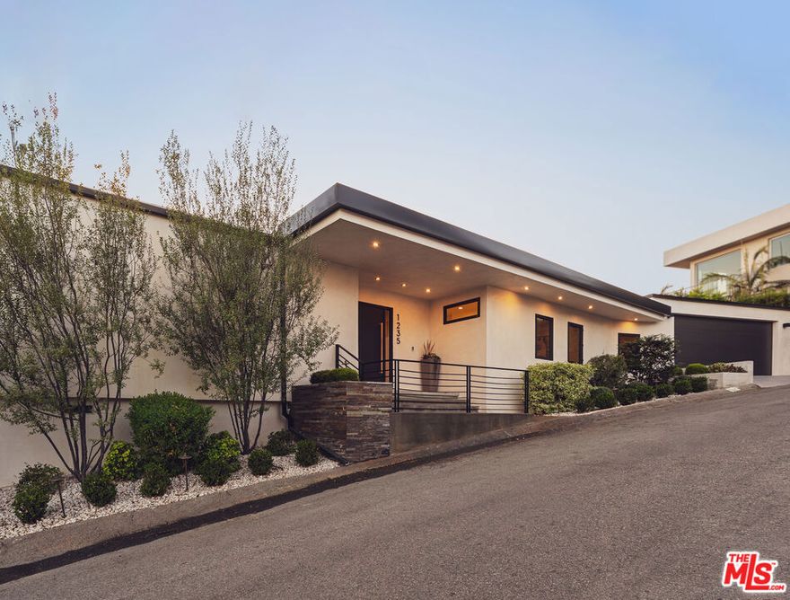 Tucked away in the hills of Kenter Canyon, this single-story modern compound in the exclusive Crestwood Estates exudes effortless California cool. Reimagined with sleek design, sophisticated finishes, and a seamless indoor-outdoor flow, it's the ultimate private retreat for elevated living. Step inside and feel the calm as a wide-open floor plan framed by walls of glass dissolves into lush treetops and canyon views that stretch all the way to the ocean. The living room stuns with a sculptural fireplace, custom built-ins, and moody ambient lighting that sets the tone. At the heart of the home, a dedicated dining area flows into a showpiece chef's kitchen anchored by a massive island perfect for cooking, entertaining, or late-night conversations. Warm wood-beamed ceilings, double prep stations, Viking appliances, a wine fridge, and tailored cabinetry give the space a vibe that's both organic and refined. The primary suite is pure serenity with floor-to-ceiling sliders opening to panoramic canyon and ocean vistas, while the spa-like bath features dual vanities, intricate tilework, and a frameless glass shower with dual rainfall heads. Two additional ensuite bedrooms offer guests a five-star experience. Outside, the magic continues with expansive decks, a plunge pool, outdoor fire pit, grassy lounge area, and curated landscaping that create the ultimate year-round escape. This is where you host, unwind, and disappear from it all while staying minutes from the Brentwood Country Mart, the ocean, and everything the Westside has to offer.