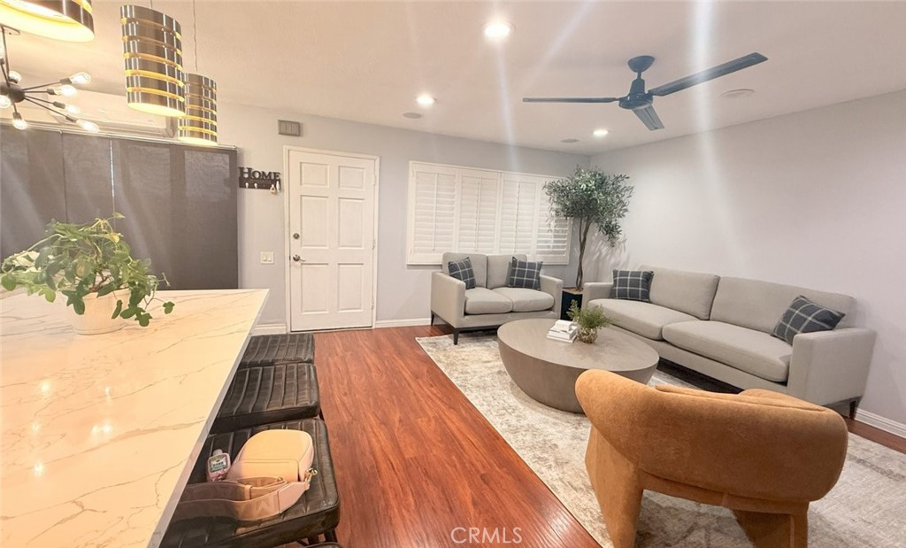 introducing this beautifully upgraded two-story townhome in the desirable Boardwalk Village community of Cerritos. Featuring 3 bedrooms, 2.5 bathrooms, and approximately 1,145 square feet of thoughtfully designed living space, this home offers modern style and comfortable functionality. The spacious open-concept main level showcases sleek laminate flooring, recessed lighting, and a bright living area with custom window shutters and roller shades for added privacy. The updated kitchen is the heart of the home, boasting white cabinetry, quartz countertops, a center island, and a cozy breakfast nook perfect for everyday dining. Upstairs, you'll find all three bedrooms, including a well-sized primary suite with a walk-in closet and two additional full bathrooms. The property also includes a surround sound wall system, central cooling, and a private outdoor patio area. Enjoy the convenience of a dedicated garage and an additional parking space. The low monthly HOA covers water, gas, trash, and landscaping—an incredible value. Boardwalk Village offers resort-style amenities including a pool, spa, and clubhouse for gatherings. Ideally located near Cerritos Mall, schools, shopping, dining, and with quick access to the 91 and 605 freeways, this is a rare opportunity to own in a peaceful and well-maintained community.