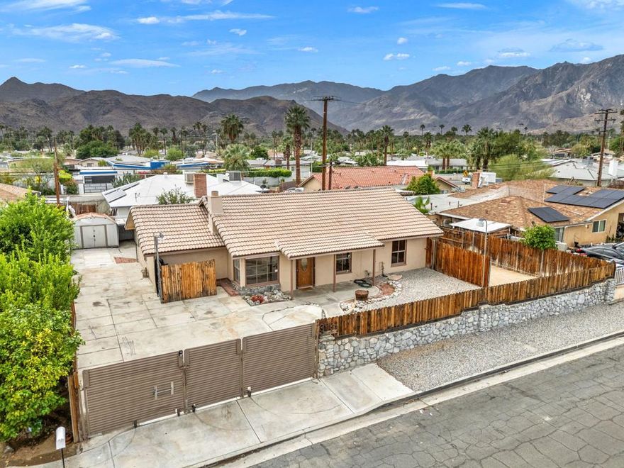 South Palm Springs, fee-simple (owned land) in Demuth Park with mountain views and RV/boat parking. This gated single-level 4BD/1.5BA, approx. 1,433 SF, blends mid-century warmth with practical updates. Enter to a light, inviting living room centered on a natural-stone, wood-burning fireplace. The kitchen features granite counters, warm wood cabinetry, and flagstone flooring; nearby flex space adds handy storage. Bedrooms are well separated, with the primary set toward the quiet rear. The 4th bedroom offers an upper/lower sleeping loft -- ideal for guests, kids, or office. Oversized main bath has dual vanities, shower-over-tub, laundry, and extra storage; a second half bath adds convenience. In the spacious yard, create your fun-in-the-sun retreat: covered patio for dining, BBQ counter, firepit zone, planters, and room to design a future pool. Driveway gates open to RV parking with sewer access; newer electrical panel and space for 220 at the RV area. No HOA, no land lease. Moments to Prescott Preserve, Demuth Park (pickleball), Smoke Tree Commons, the Airport, and downtown Palm Springs. STRs may be permitted in Demuth Park -- buyer to verify, permits, and measurements. Quiet south-end low wind spot with sunsets and quick access via El Placer, Ramon Road and Hwy111. Don't miss it.