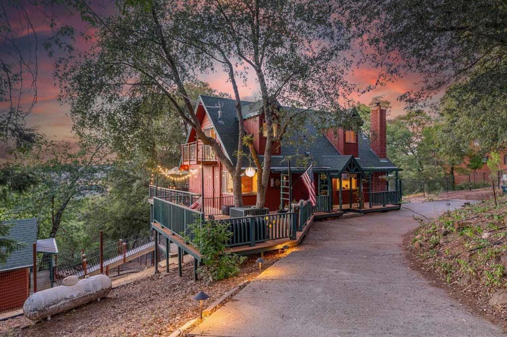Nestled among majestic oaks and pines, this custom-built home offers tranquility in the charming and peaceful neighborhood of Pine Hills. This 1.29 acre property boasts scenic vistas of nearby mountain peaks, creating an idyllic retreat. Multiple private balconies and decks provide serene spaces to unwind and immerse yourself in nature's beauty. Wood ceilings and beams grace the main living spaces complementing the beautiful rock fireplace hearth. Luxury vinyl plank flooring adds to the home's elegant appeal. The spacious basement includes a half bath and shower, making it perfect for entertaining or accommodating extra guests. A detached studio serves as an ideal office or quiet retreat. This charming home reflects an ideal country cottage feel with interior wood accents and set amongst a forest of trees. The spacious living room is adorned with a floor to ceiling rock fireplace hearth and wood beam ceiling. Large picture windows show the beautiful mountain scenery that surrounds this property. Downstairs is a full bath and bedroom sporting a murphy bed and space for a home office. Upstairs you find a remodeled walk-in shower. Two bedrooms have vaulted wood ceilings and light ceiling fans. Each bedroom has a private balcony overlooking the tree covered grounds. A bonus to this house is the large basement area which can be utilized as an entertainment center or additional sleeping area with a half bath and shower unit. There is a sliding door leading onto a private deck overlooking the back portion of the property. Separate mini-splits systems are located in the living room and in each bedroom. The detached studio has power with many possibilities such as an office or craft room. A whole house generator ensures reliable power during occasional outages. Relax on one of the deck areas to watch a movie screen on a nice warm evening. Or, sit out on a deck and enjoy the open sky full of stars. Fall brings a vast array of autumn leaves with vibrant color. Winter delivers an occasional snowfall adding delight for all to enjoy. Seasonal blooms include lilacs, wisteria and daffodils. Deer and wild turkey frequent the neighborhood enjoying the natural vegetation. Welcome to this piece of paradise!
