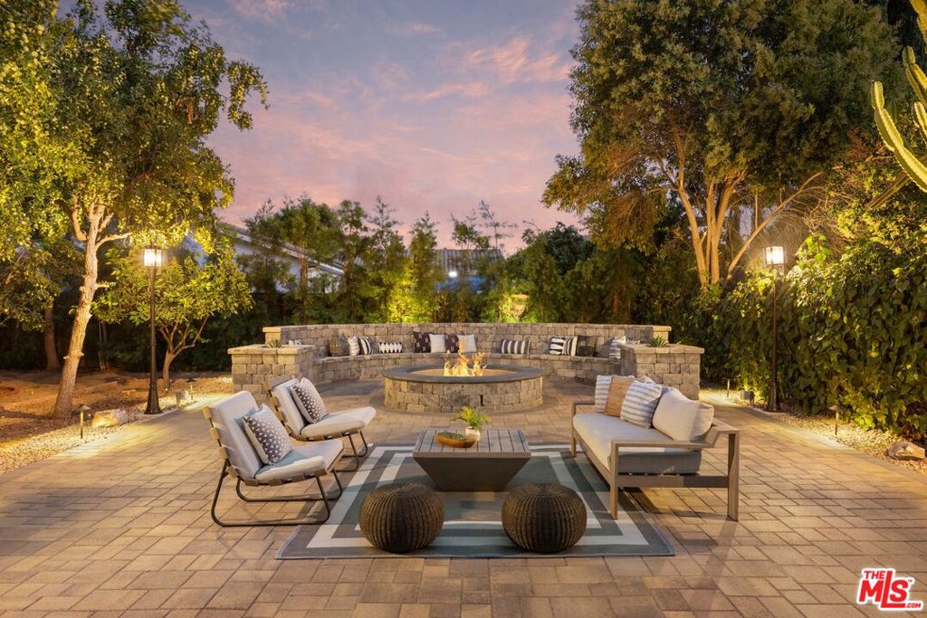 An Elegant Retreat in Walnut Acres offering the perfect balance of resort-style entertaining and private luxury living. Privacy, tranquility, and timeless elegance await you in this hidden gem, perfectly nestled on one of the most prestigious streets in Walnut Acres, Woodland Hills. From the moment you arrive, the beautifully landscaped front yard, complete with a circular driveway, sets a welcoming tone, while the expansive, secluded backyard feels like your own private resort. A sparkling pool framed by lush fruit trees and vibrant gardens creates the ultimate setting for entertaining guests or simply unwinding in complete serenity. Set on a sprawling 25,700+ sqft flat lot, this estate includes a stunning single-story ranch home complemented by a newly built ADU with its own new electrical panel, two ensuite bedrooms, a kitchenette, and 1,050 sqft of versatile living space ideal for extended family, a private office, or rental income. Inside the main residence, the remodeled gourmet kitchen is a showstopper, with quartz countertops, custom cabinetry, premium stainless steel appliances, bar seating, and seamless flow into the expansive family room with breathtaking nature views. The open layout features multiple gathering spaces, including a formal dining room, a separate living room with a fireplace, and a grand double-door stone-tiled foyer perfect for both elegant entertaining and relaxed everyday living. The private bedroom wing offers sun-filled retreats tucked away from the main living areas. Significant recent upgrades include a brand-new roof (2024), a main electrical panel upgrade from 100 AMP to 200 AMP, and modernized finishes throughout, ensuring both elegance and functionality for years to come. Outdoors, the estate transforms into a private resort. The covered stone-tiled patio offers a seamless indoor-outdoor lifestyle, while a 460 sqft bonus studio with a half bath provides endless possibilities, currently curated as a gym and massage room. All this, just moments from premier shopping, dining, entertainment, freeway access, and award-winning schools. This property is more than a residence it's a lifestyle retreat where elegance, comfort, and entertaining meet in perfect harmony. A rare Walnut Acres treasure not to be missed!