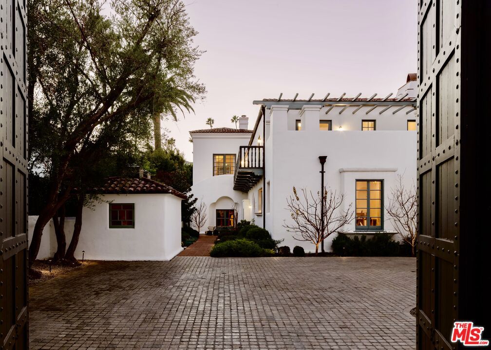 The Chimorro House (1926) Roy Seldon Price, AIA With a designation to the Beverly Hills List of Master Architects, 911 North Beverly Drive had been named for its original owner, Mrs. Chimorro, a close friend of Charlie Chaplin who courted Mr. Price to design the home before his creation of other noted landmarks of Los Angeles Writers & Artists Building, Chaplin's own studio offices (currently the dramatic space of Republique), and the private residence of Thomas H. Ince. The property has always been distinguished by its iconic "Jurassic Park" gates and was initially built in the early 20th Century and used as one of the few private Prohibition houses of the time, purportedly with a direct underground tunnel conveniently leading to the Beverly Hills Hotel, just a block away. The Chimorro Estate has previously been published in various design portfolios including C California Style Magazine and the Los Angeles Times . In its most recent half-decade, the current owner has completed a thoughtful and carefully considered restoration of the historical property, a stunning example of early 20th-century Beverly Hills Spanish Revival architecture and showcases arched walls, vintage ironwork, and hand-painted California tiles throughout. The estate lives just shy of 6500sf - features 6 bedrooms, large theater, wine room, game room and dual powder rooms. Generously scaled spaces are suited perfectly for showcasing large-format art and sculpture. A plot measuring almost a half-acre, the property also includes a detached guest house along with the former original guard gatehouse, which has since been used as a tearoom, office, and lounge. The original oversized oval pool immortalized in an early mid-century Slim Aarons photograph enjoys privacy from all three mature hedges. A spacious two-car garage sits at the other side of a courtyard with parking for 8-10 cars behind the gates.