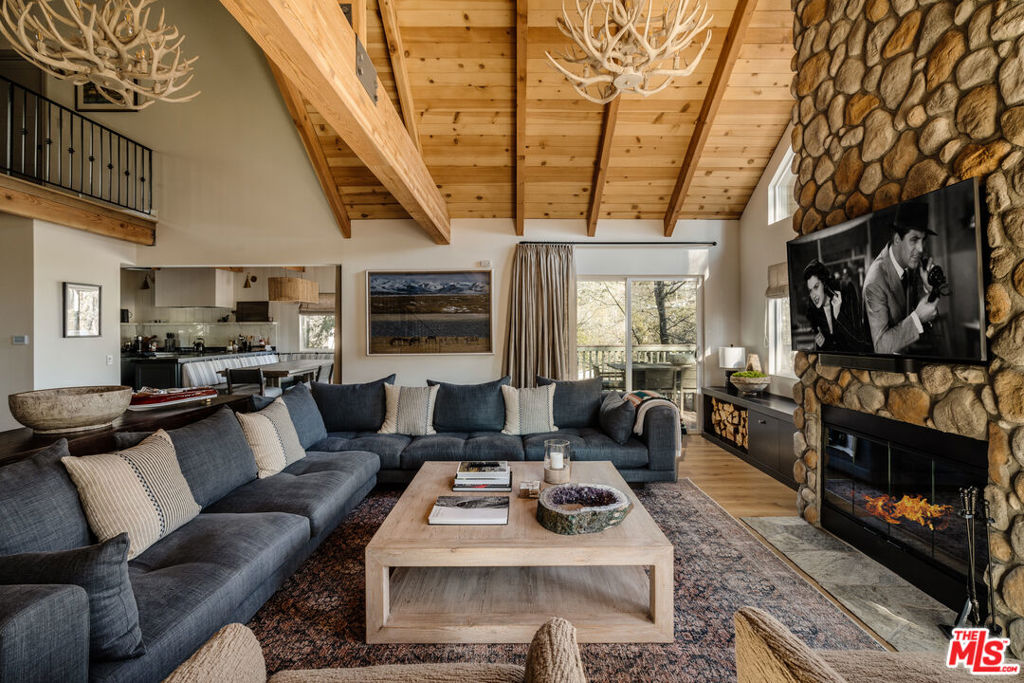 Beautifully remodeled and fully furnished, this turnkey Lake Arrowhead home is located in the prestigious gated community of North Shore Estates. Designed by an award-winning designer in close collaboration with the homeowner, the residence exudes elevated mountain style with curated finishes, custom details, and a warm, inviting aesthetic. With generous indoor and outdoor living spaces, modern upgrades, and rare short-term rental eligibility, this is a true four-season retreat just 2 hours from most SoCal cities.The main living room welcomes you with soaring wood-beamed ceilings, a striking floor-to-ceiling stone fireplace, and an inviting, relaxed energy. A whimsical swing in the entryway sets the toneleave your worries at the door. The chef's kitchen is fully remodeled with custom cabinetry, premium finishes, and a charming built-in dining nook, perfect for cozy mornings or festive evenings. A main-level bedroom offers convenience and flexibility, while two additional upstairs bedrooms feature vaulted ceilings and peek-a-boo lake views through the trees.Overlooking the main living area is a lovely library loft, ideal as an office or reading space. On the lower level, a stylishly renovated den with its own fireplace includes a custom pull-out sofa bed and a full bath, making it a comfortable and private fourth sleeping area for guests.Step outside to enjoy multiple outdoor spaces, including a large front deck, an oversized back deck, a lower patio, and your own private hot tuball surrounded by mature oaks, pines, and vibrant maple trees. Whether you're sipping morning coffee or stargazing at night, you'll be immersed in nature.Additional upgrades include smart home features with keyless entry and remote thermostat access, A/C, an EV charger, and a water filtration system in the kitchen. Parking is generous with a private driveway, attached one-car garage, and space for guests and a boat.Also available for separate purchase: a 1/3 ownership of a dock slip (the closest slip to the home) and a well-maintained deck boat. Shared ownership in a dock house is also included, an architecturally notable structure designed by David C. Fowler and photographed by Julius Shulman. This is your chance to own a fully furnished, designer-renovated mountain home in one of Lake Arrowhead's most desirable lake-access communities.