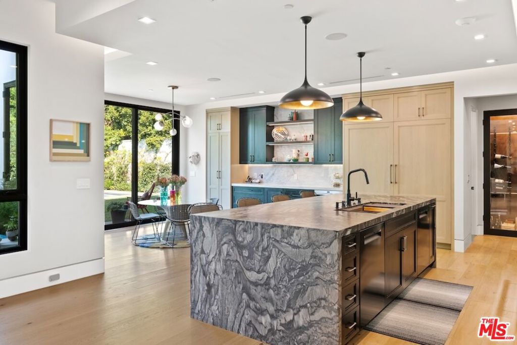 Tucked away in the prestigious Riviera neighborhood of Pacific Palisades, this stunning move-in ready modern home offers over 6,500 square feet of refined living space on a 15,000-square-foot lot. Set behind private gates and surrounded by mature landscaping, the property provides both seclusion and elegance. A grand circular driveway, lined with olive and fruit trees, sets the tone for the home's sophisticated design. Inside, the residence is thoughtfully designed with five bedrooms and seven bathrooms, blending natural materials with contemporary architecture. The kitchen is a chef's dream, centered around a custom Le Cornue range and oven, complemented by high-end appliances and sleek finishes. The open-concept living spaces flow effortlessly, enhanced by large dual-pane windows that bathe the interiors in natural light. A private elevator connects all levels, leading to a striking bar room with an Onyx countertop and a wine closet with temperature controls. A hidden door discreetly reveals a state-of-the-art home theater, complete with an 8K projector, surround sound system, and motion-sensing ambient lighting. The primary suite offers a spacious retreat with a sitting area, dual walk-in closets, and a spa-like bathroom finished in luxurious marble. Outside, the backyard is designed for both relaxation and entertaining, featuring a large pool and spa, a custom fire pit, and a lush lawn. A built-in Kalamazoo K750 Hybrid Fire grilling station with a double cooktop completes the outdoor experience, ideal for alfresco dining. Located just moments from The Riviera Country Club, Brentwood Country Mart, top-rated schools, and renowned dining, this home offers a rare opportunity to own a modern architectural gem in one of Los Angeles' most sought-after neighborhoods.