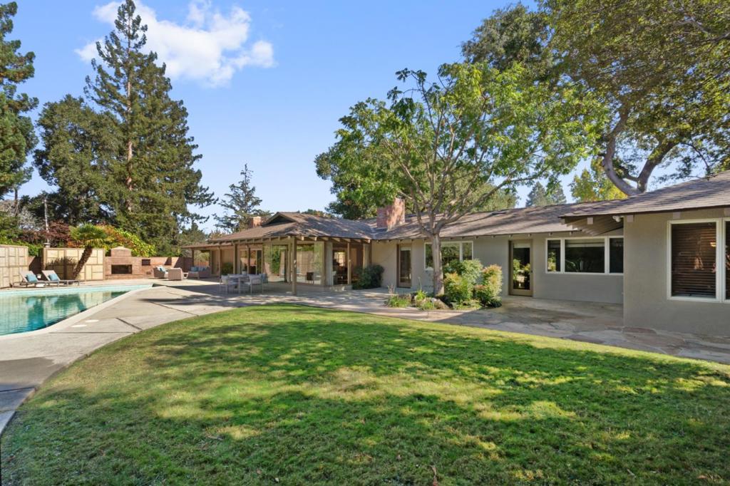 Nestled at the end of a private driveway, this mid-century modern 4-bedroom, 3.5-bath home rests on an expansive 23,791 square foot flag lot in desirable West Menlo Park. Natural light fills the home through a generous use of skylights, picture windows and sliding glass doors. The spacious rear yard with mature landscaping and pool is a focal point of the home and is accessible from most rooms. The single level design presents the perfect backdrop for both everyday living and entertaining. The foyer opens to the spacious living room and adjacent dining room. The kitchen connects seamlessly to this space as does the family room which has a convenient pocket door if separation is desired. A bedroom and full bath, located just off the kitchen, creating an ideal arrangement for guests.