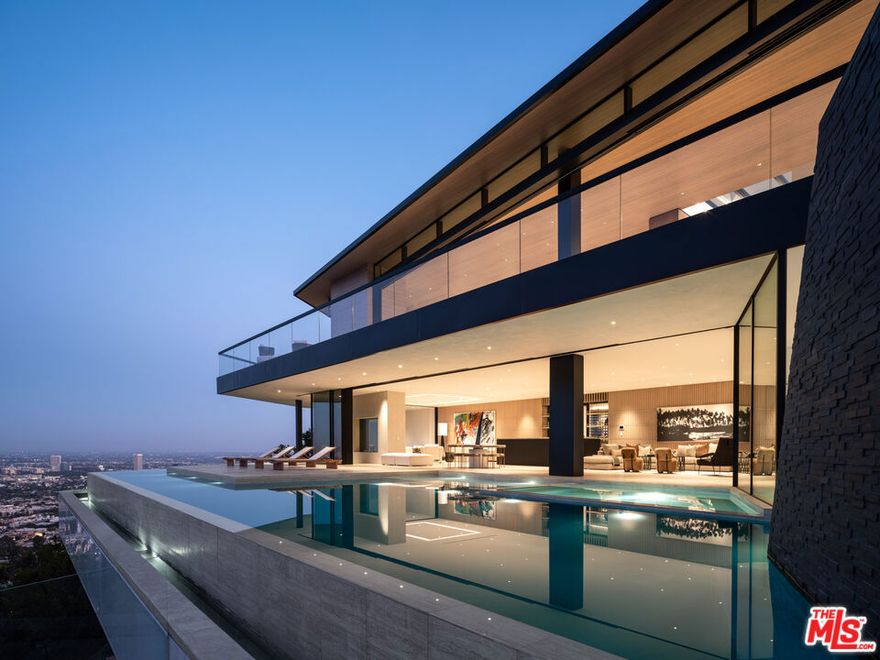 Sited on the most prestigious cul-de-sac in the famed Bird Streets, this remarkable modern home designed by Vantage Design Group features the finest finishes, incredible volume, and jetliner views over the Los Angeles basin. A discreet facade leads to the upper level via a skylit foyer framing the perfect entry to a dramatic living space. Disappearing walls of glass create an idyllic indoor/outdoor entertainment area with panoramic views. Honed travertine, walnut millwork, and natural materials create a warm aesthetic blending seamlessly to the expansive outdoor deck. The home features a bar, spa, and multiple seating areas. The second level entertaining area is framed by a jaw-dropping infinity pool featuring a baja shelf, a cascading water wall, and a spa where one can soak amongst the sparkling city lights. A gorgeous Jade bar sits in front of a beautiful walk-in wine room, perfect for entertaining guests. The spacious private primary suite features a generous walk-in closet and opens to its own lounging deck with an outdoor fire pit. Lower level guest suites and a maid's quarter all feature stunning bathrooms and sweeping city views. Additional amenities include an elevator, smart home system, large gym with yoga area overlooking an atrium, steam room, dry sauna, outdoor pool bathroom, and bbq. 5+ years in the making, a true trophy in a blue-chip location.