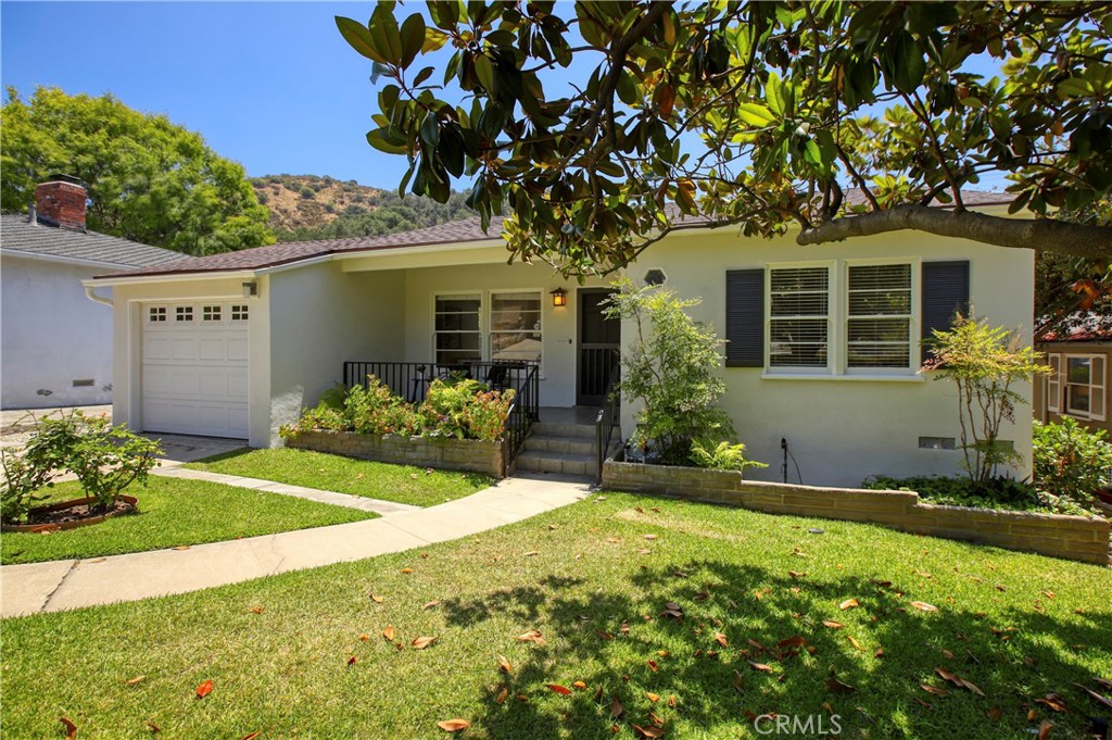 In 1940, Francis M. Simons selected this parcel in the Verdugo Woodlands on which to construct her beloved character cottage. She sited the house purposefully on this parcel to maximize the yard space while creating a sense of seclusion within it.
Greeted at the front door within a welcoming front porch, you are invited into the formal living room with its rich hardwood floors and character wood windows that fill the home with natural light. The oversized kitchen is a wonderful surprise with its updated tile flooring, granite counter tops, and a wall of glass overlooking the romantic covered patio and the view beyond. Both bedrooms are off the main hall with a den in the middle that could function as a third bedroom as well. The full bath has been tastefully updated and the primary bedroom has its own primary bath.
The rear yard is a wonderful surprise with lawn play space, pampered gardens, mature trees and a lovely view. There is also a small storage area around the back that could make for a clever home office. Just a few of the features include central air and heating, a new roof, laundry area off the main hall, and an attached garage. Per the GUSD website, this property is within the Fremont Elementary, Rosemont Middle, and Crescenta Valley High School districts.