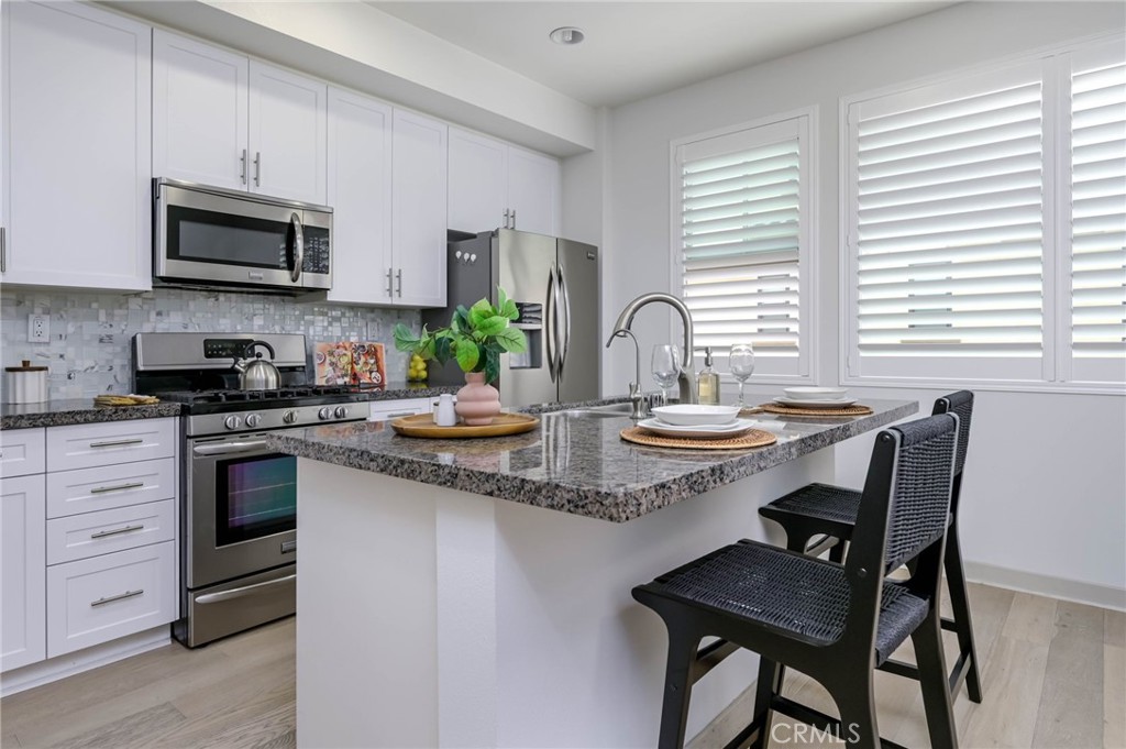 Contemporary 3-Bedroom, 2.5-Bathroom Townhome in the Heart of Anaheim. Welcome to this beautifully designed townhome offering 3 bedrooms and 2.5 bathrooms in a well-maintained community. This stylish home features high quality neutral-toned wood flooring, soaring ceilings, recessed lighting, and double-pane windows with both wooden shutters and roll-shade blinds for privacy and comfort. The spacious kitchen includes ample cabinetry, granite countertops, a center island, and a complete suite of appliances—refrigerator, gas range, dishwasher, and beverage refrigerator—all included. Upstairs, you'll find all three bedrooms, including a generous primary suite with an extra-large walk-in closet and private balcony with automatic blinds. The bathrooms are finished with white marble-style quartz countertops and white shaker cabinet vanities, offering both elegance and functionality. Designer-style ceiling fans are found in every room. An LG stacked front-loading washer and dryer are conveniently located upstairs. The home is wired with an Ethernet network, with ports available throughout the house. The attached direct access two-car garage features epoxy-coated flooring and is equipped with a tankless water heater, water softener, and EV car charging station for modern convenience. This home is just blocks from the vibrant Anaheim Packing District, with its endless culinary options, and offers easy access to the 5, 57, and 91 freeways. Popular destinations such as Disneyland, Angel Stadium, The Grove, the Gardenwalk, and the Honda Center are just short drives away, making this location ideal for enjoying all that Anaheim and the surrounding area have to offer.