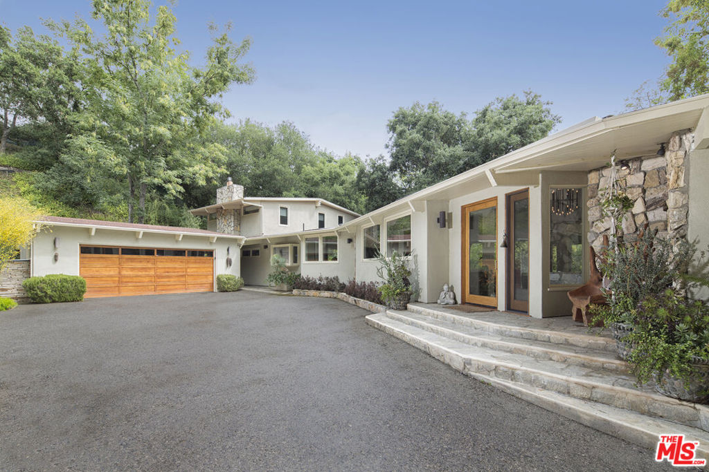 Sequestered up a long gated drive, this exquisitely renovated Mid-Century estate delivers true privacy and effortless indoor/outdoor living. Walls of glass frame oak-studded grounds across an expansive ~0.83-acre lot, creating serene sight lines from nearly every room. Inside, generous open spaces include a chic step-down living area with fireplace and a versatile family/den/home-theater ideal for everyday lounging or screening nights. The pristine center-island kitchen anchors the home and flows easily to outdoor dining and entertaining. The flexible layout offers two luxurious bedroom suites plus two additional bedrooms, for a total of 4 bedrooms and 5.5 baths. Outside offers resort-style grounds with heated pool and spa, outdoor shower, fire pit, and expansive al-fresco patios - your own private compound moments from Beverly Hills.