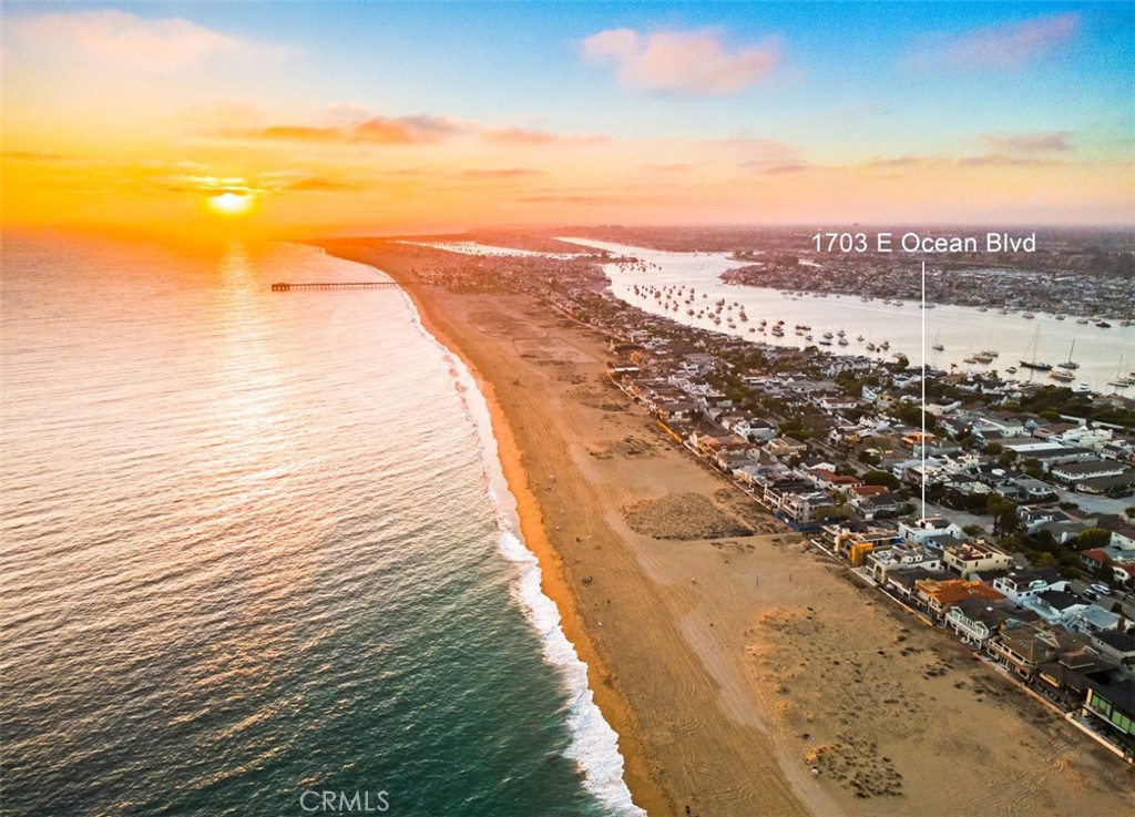 Perfectly positioned on a coveted prime corner lot on the Balboa Peninsula Point, 1703 East Ocean Blvd. is a rare coastal offering with unobstructed ocean views—one of only four properties in the neighborhood to enjoy this vantage point without being oceanfront. Just steps from the sand and surf and bay, this striking custom residence blends timeless architecture with refined finishes for a lifestyle defined by luxury and seaside ease. Designed for seamless indoor-outdoor living, the home is enclosed in floor-to-ceiling Riviera Bronze doors and windows, a smooth hand-plastered façade, and pivoting front entry that set a dramatic architectural tone. Inside, natural light floods the open layout across three levels, connected by a private elevator. Wide-plank European white oak floors, diamond-blasted concrete, real honed marble stone surfaces, and artisan custom millwork in bleached walnut and oak lend richness to every detail. Spanning 3,452 square feet across three thoughtfully designed levels, the home offers four bedrooms and five bathrooms. The chef’s kitchen is a true centerpiece, featuring Sub-Zero refrigeration, Wolf professional range, Bosch dishwasher, and expansive storage with a walk-in pantry. Entertain with ease in the indoor/outdoor dining room, where bifold doors open fully to extend living space into the coastal breeze. Four bedrooms provide flexible accommodations, while the ocean-view rooftop terrace—with gas firepit, built-in BBQ, and marine-grade finishes—offers the ultimate setting to gather for sunsets over the Pacific. Smart home technology with Control4 automation, monitored security with 7 cameras, two laundry areas, and an oversized three-car garage ensure both comfort and convenience. Every space reflects thoughtful craftsmanship, from mortised unlacquered brass hardware and custom lacquer paneling in Farrow & Ball’s “Hague Blue” to luxury fixtures throughout the baths. Balboa Peninsula Point is a destination like no other, where surf, harbor, and community come together. At 1703 East Ocean Blvd., architectural sophistication meets an irreplaceable ocean-close location for a truly timeless Newport Beach lifestyle.