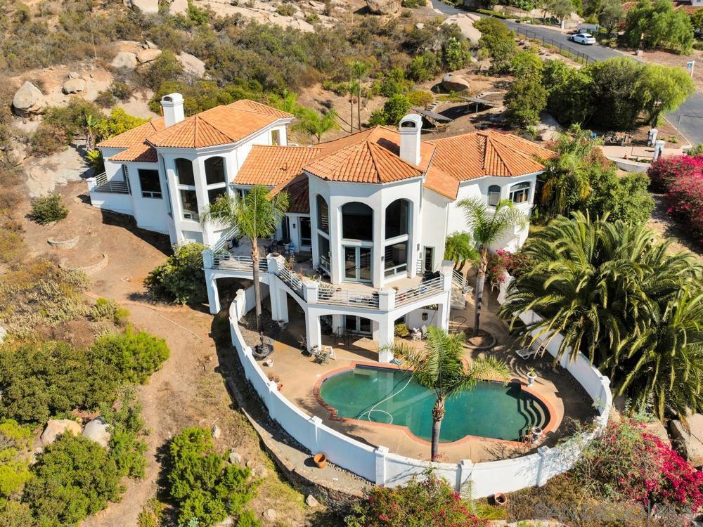 Set within the exclusive gated community of Rimrock Estates, this custom 2-story residence offers 3 bedrooms, 3.5 baths, and an expansive 5,413 sq. ft. of living space on 1.27 acres with spectacular views. A circular driveway and private courtyard lead to the impressive entry, where soaring ceilings introduce grand living and entertaining spaces anchored by multiple fireplaces. The main level features a chef’s kitchen with impressive scale, abundant cabinetry, walk-in pantry, bar, and oversized laundry room, complemented by a formal dining room, executive office, and spacious living areas designed for both gatherings and everyday comfort. The primary suite includes its own sitting area with fireplace, oversized walk-in closet, dual vanities, soaking tub, and separate shower. The lower level offers additional bedrooms, full baths, and a secondary living room with French doors that open directly to the pool and outdoor entertaining areas. Additional highlights include a 4-car garage, solar panels, fruit trees, and resort-style outdoor living. With timeless design and incredible scale, this home offers an outstanding opportunity to update and personalize in one of Escondido’s premier communities.