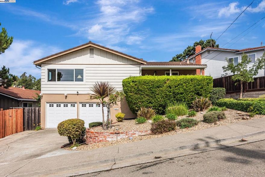 Step into this lovingly maintained home in a peaceful neighborhood where warm hardwood floors guide you through bright, comfortable living spaces. Sunlight filters through energy-efficient dual-pane windows — including premium Andersen windows — creating a cheerful, quiet interior while helping reduce utility costs. The updated kitchen is a chef’s delight with quartz countertops, a tumbled-tile backsplash, built-in gas cooktop and a built-in self-cleaning oven. A generous work island centers the space and opens to an eating area, where sliding glass doors lead to a private deck overlooking serene hilltop views — perfect for morning coffee or evening entertaining. The owner’s suite offers privacy and convenience with mirrored wardrobe storage and a recently remodeled bathroom. Downstairs, a spacious family room provides flexible living with direct access to a landscaped backyard, ideal for indoor-outdoor living or play. An additional downstairs bedroom and full bath make a comfortable home office, guest suite, or au pair quarters. The oversized attached garage includes abundant storage and there’s clear potential to expand or reconfigure spaces to suit your needs. Located minutes from transportation routes, this home blends everyday convenience with quiet suburban charm.