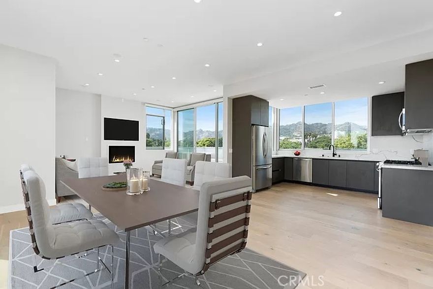 Epitomizing ultramodern luxury, this captivating penthouse in West Hollywood is a visionary masterpiece with unforgettable views reaching the Hollywood Sign. Spanning the entire 2,273 sqft top level of a high-performance building, this newly constructed condominium with smart technology showcases a distinctive style and palette that highlights its aesthetic beauty. Flooded with natural light from expansive glass, elevated living spaces are framed by floor-to-ceiling windows and retractable doors, offering an effortless indoor-outdoor lifestyle. A stunning top-of-the-line kitchen with quartz and stainless accents opens to an elegant dining and living area, creating a fashionable venue for entertaining. Inspired by the ethos of five-star resorts, dual primary suites expand to include tailored closets and lavish baths. Finished with muted European oak floors, secure parking, and multiple decks, this sleek home is the apex of jet-set chic. Soak up the sun or revel under the stars on the private 1,000 sqft rooftop deck oasis, which features a fireplace, television and bubbling spa tub. Craft mouthwatering meals on the stylish outdoor kitchen barbecue and dine alfresco with the Hollywood Hills as your backdrop. Moments from L.A.’s legendary entertainment, this picturesque environment celebrates a high walk score of 93. Surrounded by the Sycamore District and blocks from the epicenter of iconic landmarks, the locale embodies the essence of Hollywood.