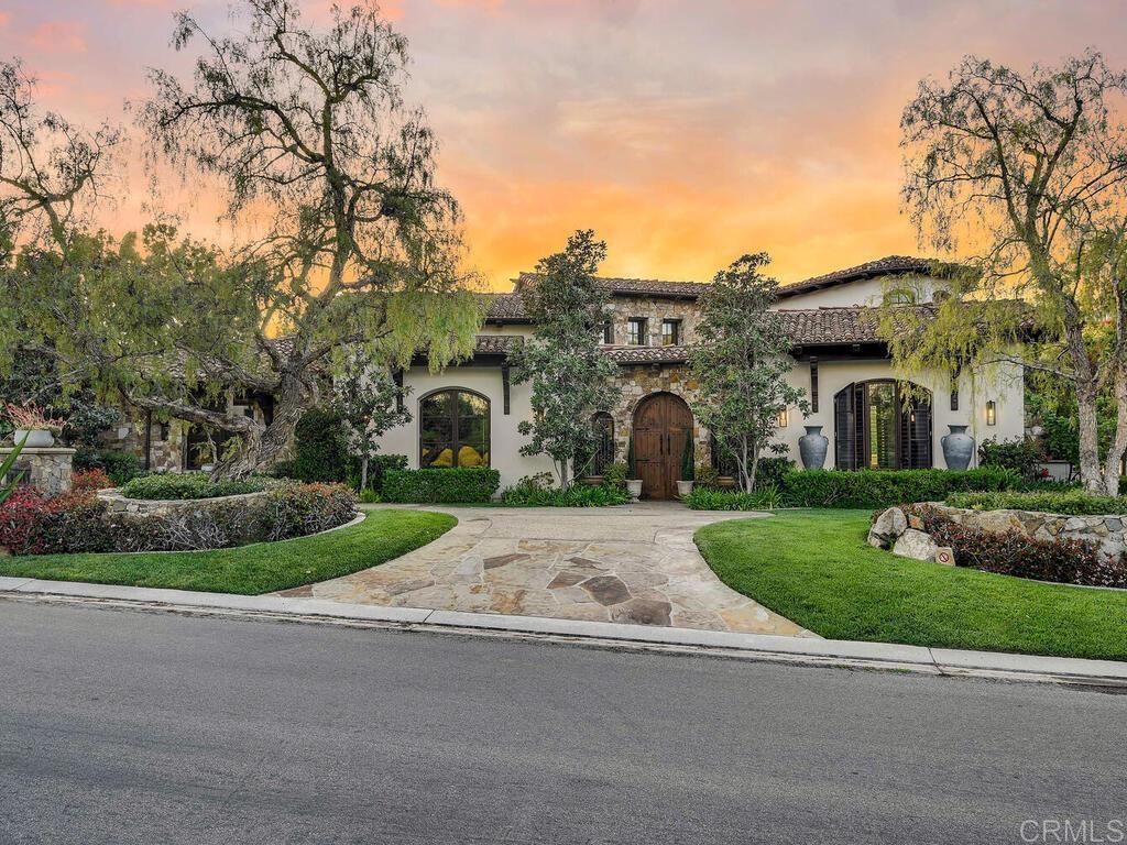 Nestled within the prestigious guard-gated community of The Bridges at Rancho Santa Fe, this custom-built estate captures the essence of luxury living in one of Southern California’s most coveted golf and tennis enclaves. Perfectly positioned above the 9th fairway, the home offers sweeping views of the clubhouse, a tranquil lake, and a lush vineyard — a serene backdrop that defines the Rancho Santa Fe lifestyle. Crafted with timeless natural stone and rich architectural details, the residence seamlessly blends indoor and outdoor elegance. Soaring wood-beamed ceilings, iron chandeliers, and chiseled travertine flooring enrich a spacious, open-concept layout designed for effortless living and entertaining. The primarily single-level floor plan is anchored by a sumptuous main-floor primary suite featuring a spa-inspired bath, dual custom walk-in closets, dual dressing areas and water closets, and direct access to a private pool, spa, grotto, and waterfall — your own secluded retreat. Additional highlights include attached guest casita, a secondary bedroom, a dedicated office/library, formal dining room, and a chef’s kitchen with stunning views. Upstairs, a large en-suite guest bedroom offers added privacy, complete with a balcony with stunning views. Step outside to a covered backyard loggia with a cozy fireplace — the ideal setting for enjoying sunset views and entertaining in style. This home is a rare opportunity to own in The Bridges, where refined living meets relaxed sophistication. Square footage has been updated to reflect public records and architectural floor plans and may differ from actual square footage. All measurements and information are deemed reliable but are not guaranteed. Listing broker, listing agent, and Seller make no representation or warranties regarding the accuracy of any information. Buyer to conduct their own investigations and rely solely on their findings