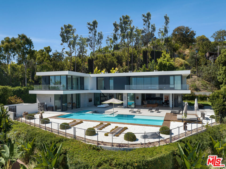 This exceptional modern estate in the heart of Beverly Hills seamlessly blends indoor and outdoor living with breathtaking city and ocean views. A dramatic two-story entrance with an indoor koi pond sets the stage for a home that exudes both luxury and tranquility. Designed for ultimate entertaining, the main level features a formal living room, built-in bar, spacious dining area, and a gourmet kitchen that flows effortlessly into the family room. Thoughtfully designed sliding glass doors flood the home with natural light while allowing flexible privacy. A custom soundproof ceiling enhances the serene ambiance. Two of the seven bedrooms are conveniently located on the main floor. Upstairs, the primary suite offers unobstructed, panoramic views, dual spa-inspired bathrooms, and expansive walk-in closets, along with four additional ensuite bedrooms. Set on 32,000 square feet of prime Beverly Hills land, the resort-style backyard boasts a zero-edge pool, lush lawn, built-in BBQ area, and a private putting green perfect for entertaining or relaxation. Complete with smart home automation and security cameras, this gated estate sits at the end of a private cul-de-sac, ensuring ultimate privacy. This turnkey luxury retreat is an unmissable opportunity for the discerning buyer.
