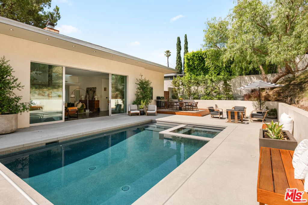 Step into modern sophistication with this light-filled custom home tucked away on a peaceful cul-de-sac. Designed for seamless living and entertaining, the open floor plan flows effortlessly to a private backyard retreat with pool and spa. The spacious primary suite opens directly to the outdoors, offering the ultimate sanctuary. A striking fireplace highlights the living room, while panoramic glass doors erase the boundary between inside and out. The gourmet Euro-style kitchen, finished with Viking appliances, granite counters, and sleek cabinetry, is a chef's delight. Beautiful hardwood floors, central air, and a direct-entry two-car garage complete this stylish home. Whether hosting lively gatherings or enjoying tranquil evenings, this residence blends elegance with comfort at every turn.