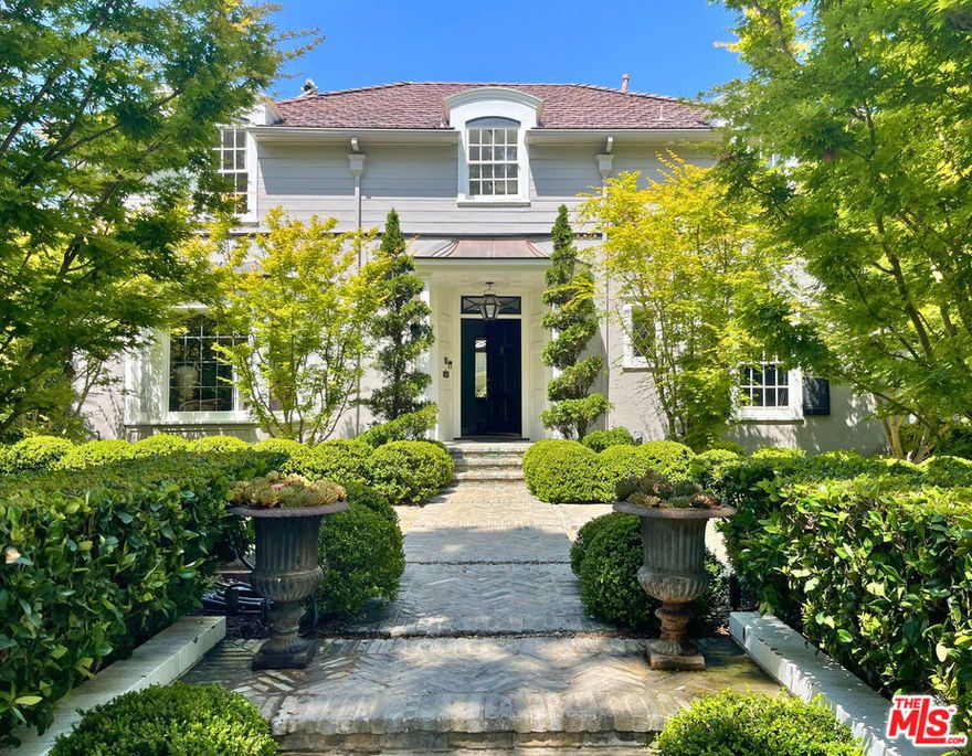 This classic 1930s home is reminiscent of a Paul Williams design perfectly located in Santa Monica Flats north of Montana. Surrounded by exquisitely landscaped gardens designed by Scott Shrader, the property offers a serene retreat with mature plantings, sculptures, curated greenery, and a magical Koi pond with lilies leads you to the front door. A welcoming foyer leads to a gracious formal living room with built-ins and a fireplace, a cozy dining room ideal for gatherings, and a sunlit kitchen all three spaces featuring French doors that open to the formal outdoor living areas, creating effortless indoor-outdoor flow. A butler's pantry and a quiet library-style office with an adjacent powder room complete the main level. Upstairs, the primary suite includes a fireplace and en-suite bath, along with two additional bedrooms and a flexible bonus room. At the rear of the property, a detached guest cottage offers a bedroom, bathroom, laundry with a light airy gym/media room all oriented toward the lush backyard. The outdoor area is anchored by a pool, spa, a cool fire pit with abundance of seating, and enclosed and privatized by a peaceful garden lined with paths of vibrant foliage. Ideally located between Montana Avenue and the Brentwood Country Mart, this elegant home offers classic architecture, privacy, and a deep connection to nature all in one of the Westside's most desirable neighborhoods.