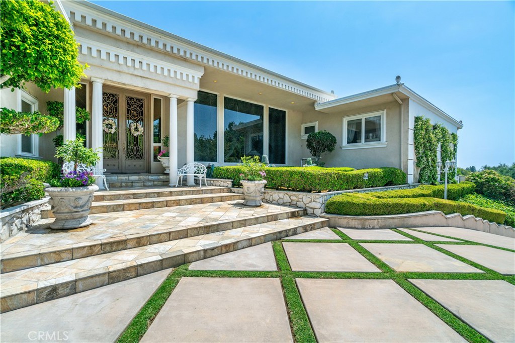 Welcome to a rare opportunity in the prestigious Friendly Hills neighborhood of Whittier. This expansive 6,313 square foot estate blends the timeless elegance of Hollywood Regency and Neoclassical Revival architecture with tasteful modernist influences. Featuring four spacious bedrooms, six bathrooms, an expansive pool, and a separate pool house with its own bathroom, this home offers both grandeur and versatility. Just a few steps down from the main level, a generously sized great room awaits—complete with a full wet bar and its own bathroom—perfect for entertaining, relaxing, or hosting in style.
Set on a picturesque, tree-lined street with wide lawns and lush landscaping, the setting feels straight out of a movie. Friendly Hills is known for its charm and character, where no two homes are alike. You’ll find everything from Mediterranean and Craftsman to midcentury ranch and contemporary styles, creating a custom-home community that’s as unique as it is welcoming.
Inside, marble floors grace the entrance of the main living area and Swarovski crystal chandeliers glisten and mesmerize throughout, setting a tone of luxury and warmth. The gourmet kitchen is a true centerpiece, appointed with sleek marble countertops, a marble stone backsplash, and top-of-the-line appliances including a Sub-Zero refrigerator and freezer, induction cooktop, gas range, dual ovens, steamer, deep fryer, and built-in icemaker—everything you need to host on any scale.
Two garages—one side-by-side two-car and another tandem two-car—both provide direct access into the home for convenience and security. Every corner of this estate is designed for effortless living, with soaring ceilings, rich textures, and elegant architectural details that reflect the glamour of Old Hollywood while offering all the function of modern design.
Outdoors, the private backyard serves as a resort-style retreat with a sparkling pool, spa, and beautifully manicured grounds. The fully equipped pool house adds exceptional flexibility, ideal for guests, a home office, or creative studio.
Adding even more value, the home is located within the highly rated boundaries of Murphy Ranch Elementary, Granada Middle School, and La Serna High School—each known for academic excellence and community involvement.
This is more than just a home—it’s a legacy property in one of Whittier’s most desirable neighborhoods, offering beauty, function, and an unmatched lifestyle.