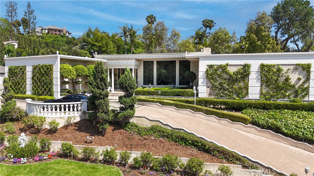 Welcome to a rare opportunity in the prestigious Friendly Hills neighborhood of Whittier. This expansive 6,313 square foot estate blends the timeless elegance of Hollywood Regency and Neoclassical Revival architecture with tasteful modernist influences. Featuring four spacious bedrooms, six bathrooms, an expansive pool, and a separate pool house with its own bathroom, this home offers both grandeur and versatility. Just a few steps down from the main level, a generously sized great room awaits—complete with a full wet bar and its own bathroom—perfect for entertaining, relaxing, or hosting in style.
Set on a picturesque, tree-lined street with wide lawns and lush landscaping, the setting feels straight out of a movie. Friendly Hills is known for its charm and character, where no two homes are alike. You’ll find everything from Mediterranean and Craftsman to midcentury ranch and contemporary styles, creating a custom-home community that’s as unique as it is welcoming.
Inside, marble floors grace the entrance of the main living area and Swarovski crystal chandeliers glisten and mesmerize throughout, setting a tone of luxury and warmth. The gourmet kitchen is a true centerpiece, appointed with sleek marble countertops, a marble stone backsplash, and top-of-the-line appliances including a Sub-Zero refrigerator and freezer, induction cooktop, gas range, dual ovens, steamer, deep fryer, and built-in icemaker—everything you need to host on any scale.
Two garages—one side-by-side two-car and another tandem two-car—both provide direct access into the home for convenience and security. Every corner of this estate is designed for effortless living, with soaring ceilings, rich textures, and elegant architectural details that reflect the glamour of Old Hollywood while offering all the function of modern design.
Outdoors, the private backyard serves as a resort-style retreat with a sparkling pool, spa, and beautifully manicured grounds. The fully equipped pool house adds exceptional flexibility, ideal for guests, a home office, or creative studio.
Adding even more value, the home is located within the highly rated boundaries of Murphy Ranch Elementary, Granada Middle School, and La Serna High School—each known for academic excellence and community involvement.
This is more than just a home—it’s a legacy property in one of Whittier’s most desirable neighborhoods, offering beauty, function, and an unmatched lifestyle.