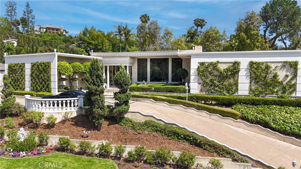 Welcome to a rare opportunity in the prestigious Friendly Hills neighborhood of Whittier. This expansive 6,313 square foot estate blends the timeless elegance of Hollywood Regency and Neoclassical Revival architecture with tasteful modernist influences. Featuring four spacious bedrooms, six bathrooms, an expansive pool, and a separate pool house with its own bathroom, this home offers both grandeur and versatility. Just a few steps down from the main level, a generously sized great room awaits—complete with a full wet bar and its own bathroom—perfect for entertaining, relaxing, or hosting in style.
Set on a picturesque, tree-lined street with wide lawns and lush landscaping, the setting feels straight out of a movie. Friendly Hills is known for its charm and character, where no two homes are alike. You’ll find everything from Mediterranean and Craftsman to midcentury ranch and contemporary styles, creating a custom-home community that’s as unique as it is welcoming.
Inside, marble floors grace the entrance of the main living area and Swarovski crystal chandeliers glisten and mesmerize throughout, setting a tone of luxury and warmth. The gourmet kitchen is a true centerpiece, appointed with sleek marble countertops, a marble stone backsplash, and top-of-the-line appliances including a Sub-Zero refrigerator and freezer, induction cooktop, gas range, dual ovens, steamer, deep fryer, and built-in icemaker—everything you need to host on any scale.
Two garages—one side-by-side two-car and another tandem two-car—both provide direct access into the home for convenience and security. Every corner of this estate is designed for effortless living, with soaring ceilings, rich textures, and elegant architectural details that reflect the glamour of Old Hollywood while offering all the function of modern design.
Outdoors, the private backyard serves as a resort-style retreat with a sparkling pool, spa, and beautifully manicured grounds. The fully equipped pool house adds exceptional flexibility, ideal for guests, a home office, or creative studio.
Adding even more value, the home is located within the highly rated boundaries of Murphy Ranch Elementary, Granada Middle School, and La Serna High School—each known for academic excellence and community involvement.
This is more than just a home—it’s a legacy property in one of Whittier’s most desirable neighborhoods, offering beauty, function, and an unmatched lifestyle.