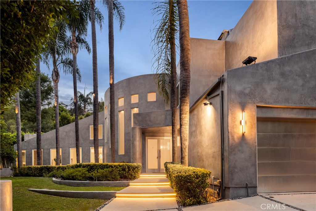 Gated and ultra-private, this 5-bedroom, 4.5-bath architectural retreat spans 4,398 sqft on a 10,733 sqft lot in prime Sherman Oaks, blending bold design with modern elegance. Defined by its sweeping curved façade, towering walls of glass, and soaring ceilings, the residence is finished with premium materials including Porcelanosa tile, imported travertine, white oak floors, and Cream Marfil Select marble. A dramatic foyer leads into expansive, light-filled living spaces, including a sophisticated formal living room, dining area, and family room with direct access to the backyard. The remodeled chef’s kitchen is a standout, featuring sleek cabinetry, a waterfall island, new under-mount sink, Sub-Zero refrigerator, and professional-grade Viking appliances. Upstairs, the luxurious primary suite offers vaulted ceilings, a private balcony, a cozy sitting area with fireplace, a large walk-in closet, and a spa-like bathroom featuring an oversized shower and soaking tub. Multiple balconies and patios create seamless indoor-outdoor flow throughout the home. The lush entertainer’s backyard boasts a sparkling saltwater pool with cascading waterfall, built-in Viking BBQ, and low-maintenance landscaping for ultimate relaxation and gatherings. Additional amenities include a 12-camera security and alarm system, neighborhood ADT patrol, new roof with skylights, and a new electrical panel. Located in the heart of Sherman Oaks - just minutes from upscale dining, shopping, hiking trails, top-rated schools, and quick freeway access - this home offers the perfect balance of privacy and convenience.