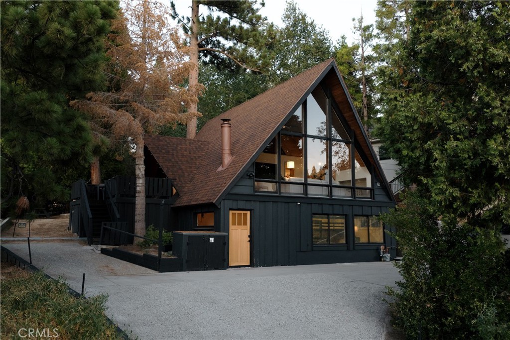 Just across from Emerald Bay, one of Lake Arrowhead’s most desirable pockets, sits an A-frame tucked among the pines. Fully renovated and in a prime location, with lake rights included. From here, you’re only a short stroll to the lake and ALA trail, two minutes to Cedar Glen, and five minutes to the Village for shopping, dining, and year-round events. Inside, a wall of windows draws your eye to the view of towering pines and peaks of the lake. Vaulted wood ceilings open up the space, while a stone fireplace keeps it cozy. The main level features the living room, dining nook, and kitchen flowing together seamlessly, plus a bedroom and bath. Upstairs offers a loft bedroom that fits two queens, while the lower level has another bedroom, bath, and mudroom with its own entry for extra privacy. The backyard is a rare find in the mountains. Flat, usable, and framed by pines, perfect for BBQs or long summer nights outside. Ample parking provides convenience and ease of access. With central AC, thoughtful updates, and a complete remodel that blends modern amenities with the cozy, iconic A-frame feel, this home is ready for its next chapter. Whether that’s as a full time residence, a vacation escape, or a smart investment with its successful short term rental history.