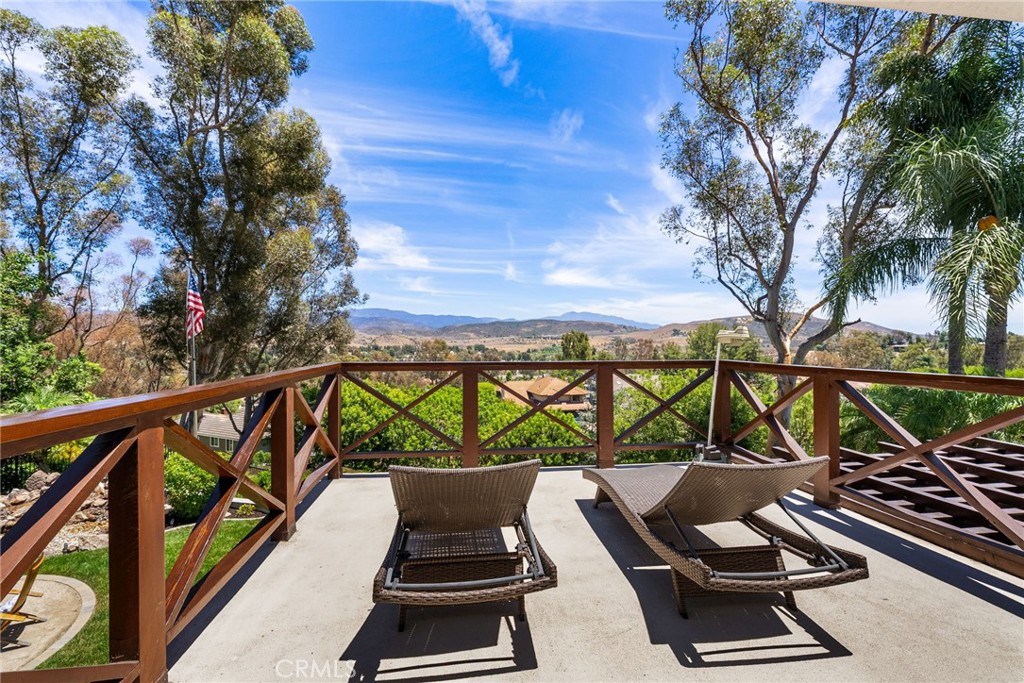 Sweeping canyon and hillside views set the tone at 9686 Ravenscroft Road in North Tustin—a beautifully upgraded 5-bedroom, 4-bathroom custom home located on a quiet cul-de-sac in the prestigious 24-hour guard-gated community of Rocking Horse Ridge. This over 3,200 sq ft residence offers a flexible layout with two bedrooms and two baths downstairs, and a luxurious upstairs retreat featuring a private balcony, generous walk-in closet, and even more panoramic views. The remodeled chef’s kitchen includes custom cabinetry, a granite island with bar seating, KitchenAid commercial appliances, dual wine coolers, and a warming drawer, flowing seamlessly into the inviting family room with a stone fireplace, leathered granite bar, and Sonos surround sound. From the main living areas, backyard, and upstairs retreat, you’ll enjoy incredible hillside scenery and natural light throughout the day. Elegant touches like cathedral ceilings, wainscoting, double barn doors, hardwood and slate flooring, and custom built-ins create a warm yet refined atmosphere. The backyard is an entertainer’s dream, complete with a covered dining patio, Twin Eagles grill, Green Egg BBQ, gas fire pit with wine barrel chairs, natural rock waterfall, outdoor Sonos sound, and soft landscape lighting. Additional upgrades include a tankless water heater, updated A/C ducting, new irrigation, custom gates, and a spacious 3-car garage with built-in storage. Enjoy access to community amenities like a pool, spa, tennis courts, sports courts, and clubhouse, along with top-rated Tustin schools and walkability to local shops, Pacific Ranch Market, and dining. This is California living at its finest—comfortable, scenic, and ready to enjoy. Welcome home!