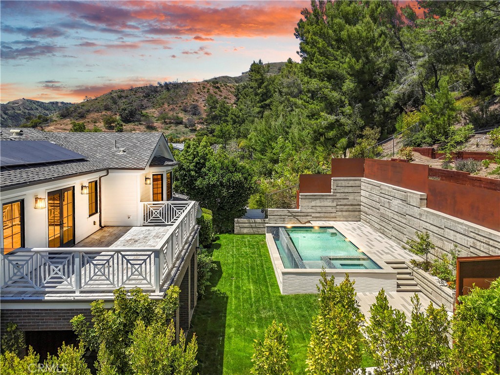 Only a 3 minute drive north of Sunset delivers you this stunning Modern Farmhouse estate in Brentwood Hills. Completed in 2020, this elegant five bedroom, six bath exquisite estate sits far back on a quiet cul de sac., spanning approx. 5,600 sqft of living and 786 sqft of covered patio on an expansive almost 20,000 sq. Ft. lot. Open space living and balconies, this amazing home showcases elegant hardwood floors throughout, generous use of stone and quartz, designer fixtures and finishes, the main floor open living space include a gourmet kitchen, formal dining room, great living room, a family room with bi-fold expansive doors that open completely to the covered heated patio, pool, BBQ and a contemporary entertaining area. A ground floor movie theater, a home office and a full bedroom suite finish the main floor with no steps. Upstairs the oversized primary retreat features vaulted ceilings, a marble fireplace, a large balcony with mountain views, a gorgeous custom closet and a spa retreat bathroom. In addition, upstairs, there are three large bedrooms, a library sitting reading area with the same unbelievable views. The primary suite overlooks the infinity pool, a fire pit, the outdoor cooking area, and the covered heated patio. The three car garage is completely finished, with overhead lighting and security. Keypad smart home controls and a solar system throughout. Within the Kenter Canyon School and Palisades Charter district, surrounded by outdoor tranquil landscape, this home is truly impressive in every way.