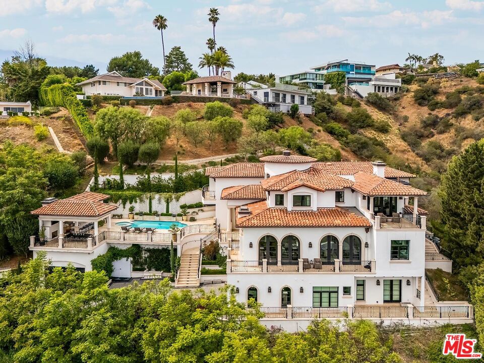 Experience the ultimate in privacy and luxury with this custom-built Bel-Air estate, showcasing designer finishes and meticulous attention to detail throughout. Enter this secluded oasis through a gated driveway leading to a spacious motor court that accommodates 5+ vehicles, plus two direct-entry 2-car garages. Spanning over 8,000 square feet, the home features 6 bedrooms and 9 bathrooms, along with a game room with bar, home theater, wine cellar, elevator, dedicated office, and a steam sauna on the lower level. The chef's kitchen is outfitted with a butler's pantry, Sub-Zero and Wolf appliances, Italian Borghini marble countertops, a large center island, and dual dishwashers. The luxurious primary suite includes a private sitting area with fireplace and opens to a large balcony offering stunning city and mountain views. It also boasts dual full bathrooms with heated floors and a generous walk-in closet. Thoughtful, high-end upgrades abound, including linear air conditioning, custom ironwork, solar panels, a gas and propane backup generator, central vacuum system, laundry chute, whole-house water filtration, five-zone HVAC, and a comprehensive security system with 16 cameras. The resort-style backyard is an entertainer's dream, featuring a spectacular pool and spa with fire features, panoramic views, a cabana with full bathroom, and a fully equipped outdoor kitchen with Viking appliances, BBQ, and dishwasher. Mature landscaping envelops the entire property, ensuring complete privacy. Home is offered unfurnished.