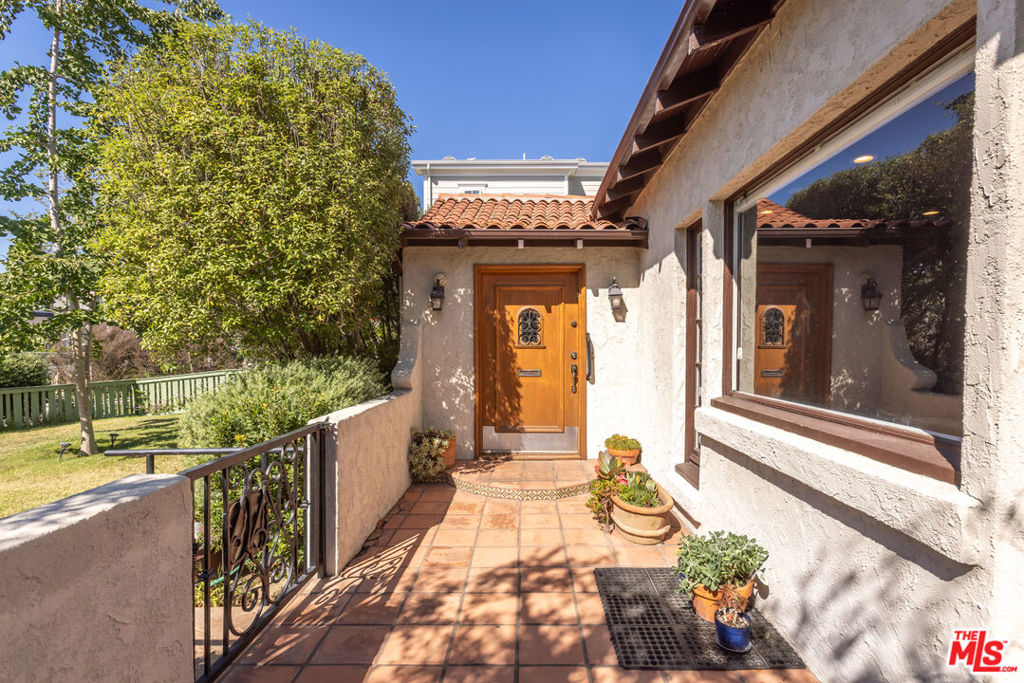 Get that Peaceful Easy Feeling. Step into timeless elegance in this wonderful Spanish Colonial Revival. Less than 400 ft. from popular running/walking route bordering Rancho Park. This one-story home is located on a picturesque, tree-lined street in one of Cheviot Hills most desirable pockets. Walk-up path includes lush lawn & sprinklers. Mature landscaping, gated driveway, and shade trees keep your fenced front yard private. Follow the path to a gated front patio and a welcoming, substantial, wood front door w/wrought iron design & stained-glass. Through the door, another stained-glass window lights the entryway. Notice the original archways set the tone for the homes true-to-era character. Enter the gorgeous grand living room. Its focal point is the huge wood-burning fireplace in original California Arts & Crafts style w/vintage Batchelder tiles. Beautiful swing open windows adorn the fireplace and face the front courtyard. Let the sunlight and perfect SoCal breezes in. Many sash windows still have that charming rope & pulley system to keep tradition. Off the living room you will find the formal dining room and then a sunroom, all leading out to the raised back deck through French doors. The deck has a jasmine covered lattice providing shade & privacy and a gate leading to the extended, level back yard mere steps below. Hummingbirds and butterflies frequent your view. The kitchen is light & bright and has been fully remodeled w/premium appliances including a great Wolf stove. Ample counter space, custom cabinetry w/slide-out drawers and shelves and a bonus large laundry room/craft room/ butler's pantry with even more storage. A door in the kitchen opens to the backyard making outdoor entertaining so easy. The thoughtful layout includes appointments like glass doorknobs and little touches to keep the integrity of the early 20th Century. The first bedroom has its own bathroom w/shower. A walk-through closet leads to the second bedroom/office. Separate tub & shower in main bathroom w/dual sinks. Primary bedroom has two large closets and French doors that open to the backyard. Enjoy the brand-new AC. Solar panels. One car garage with plenty of parking for more cars behind the remote-controlled gate and more parking in front of the gate w/access to front door, too. A serene ambiance, full of character. Your retreat is waiting. Classic Cheviot Hills, of course.