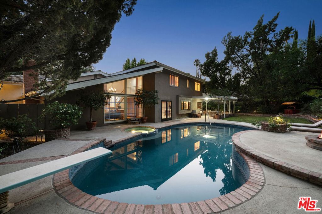 Don't miss this exceptional opportunity! Listed below recent comparable sales in the exclusive and highly coveted Hidden Estates neighborhood of Woodland Hills. Nestled on an expansive 11,000+ sq ft lot, this stunning two-story residence offers over 3,100 sq ft of thoughtfully designed living space that artfully balances elegance, functionality, and warmth. The main floor showcases a beautifully appointed primary suite featuring dual walk-in closets and a luxurious ensuite bath with an oversized steam shower and spa tub - your personal sanctuary after a long day. Bathed with natural light through expansive windows, the home exudes a sense of calm and openness throughout. The inviting living room is anchored by tongue-and-groove wood-clad ceilings and a charming fireplace, creating a cozy ambiance with seamless indoor/outdoor flow. The heart of the home the chef's kitchen is a showstopper, featuring custom white oak cabinetry, Taj Mahal quartz countertops, professional-grade appliances, and a generous center island perfect for casual dining or entertaining. It opens effortlessly into a warm and welcoming family room, where the second fireplace, adorned with an antique cast iron mantle, offers an ideal setting for gatherings large and small. Upstairs, a spacious loft provides flexible space for a media room, home office, or playroom, accompanied by three additional bedrooms and two full bathrooms. Step outside into a private, lushly landscaped backyard retreat, complete with a sparkling pool, creating a serene setting for relaxation and entertaining. The 3-car garage offers ample storage and convenience, with the third bay uniquely transformed into a theatre/ magic room - a whimsical, versatile space easily converted back if desired. Additional highlights include newer plumbing, Venetian plaster finishes, three separate AC units, solid white oak doors with custom hardware imported from England, and wide plank, Oak engineered flooring, Located just moments from Hidden Hills, this home offers rare character, space, and value in one of the most sought-after neighborhoods in Woodland Hills. If you're seeking timeless design, privacy, and a true sense of "home," this is the one.