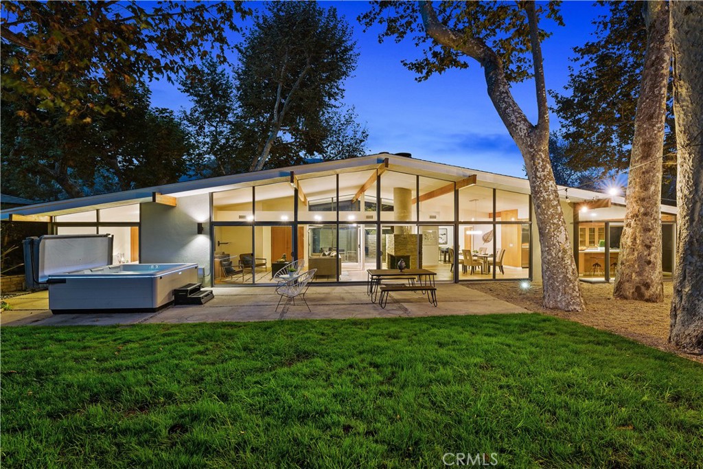 Beautifully remodeled mid-century modern in Malibu West’s sought-after “atrium-style” design with courtyard entry and floor-to-ceiling walls of glass that fill the home with natural light. Features include 3 bedrooms, an office, and a bonus room that can serve as a 4th bedroom, plus 3 updated baths. The primary suite offers a walk-in closet with custom cabinetry and shelving, and a luxurious bath with separate soaking tub and walk-in shower. The open living area centers around a fireplace and flows into the gourmet kitchen with Viking appliances. Enjoy central AC, LED lighting, whole-house water filtration, and newer flooring throughout. The spacious backyard borders a seasonal stream with majestic sycamore trees, outdoor spa, and multiple patio areas—above-ground jacuzzi with maintenance included. Includes access to Malibu West Beach Club and tennis courts.