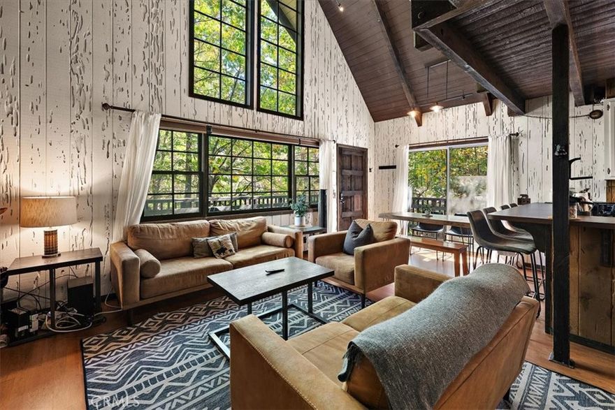 Tucked away in the serene Moonridge neighborhood, the Lazy Bear Chalet is a top rated short term rental offering the perfect blend of seclusion and convenience. Surrounded by towering trees on a peaceful street, this charming retreat is just minutes from ski resorts, the Moonridge corridor, Alpine Zoo, and the golf course. Inside, you'll find an open floor plan with huge vaulted ceilings, expansive windows that flood the space with natural light, and a stunning floor-to-ceiling wood-burning brick fireplace. The main level features a large bedroom, bathroom and complete full size laundry room, while upstairs provides secondary bedroom and a loft, providing additional space for guests or a bonus room. Recent upgrades throughout—including stylish new furnishings—enhance comfort and convenience. Step outside to enjoy the newly installed Trex decking, a brand new private hot tub, and ample parking. Nestled in a highly desirable neighborhood with year-round accessibility, this chalet boasts an excellent STR history with rave reviews. Come experience the charm of the Lazy Bear Chalet!