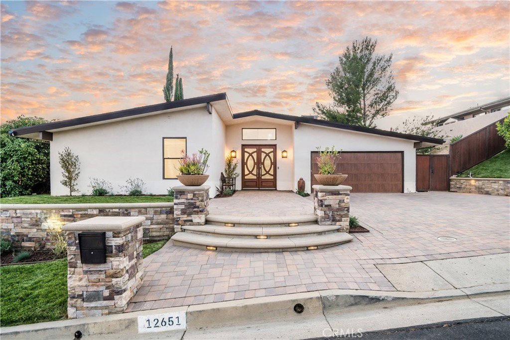 Welcome to this beautifully updated 4-bedroom, 2.5-bathroom modern View retreat located in Prime Granada Hills neighborhood North Of Rinaldi. Set on a quiet street with serene hillside views, this home blends mid-century design with luxurious indoor-outdoor living. Step inside through elegant double doors and be amazed what this true modern beauty has to offer. Natural light-filled open layout with vaulted ceilings with multiple skylights, tastefully remodeled all throughout. The spacious modern chef's kitchen with center island flows easily into the dining and living areas — perfect for family gatherings or entertaining guests. The resort-style entertainers backyard is made for California living — featuring a covered patio with a built-in TV, ceiling fans, outdoor dining and lounge area, dry sauna and a sparkling pool overlooking panoramic mountain views. Additional features include New LED recessed lights throughout, New entry chandelier and wall sconces, New interior paint throughout, Updated Central A/C & Heat, New side privacy fence, New landscaping & Sprinkler System, New Pavers and so much more. Truly A Must See!!!