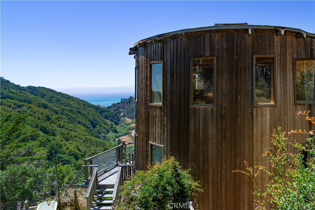 Welcome to one of the most unique offerings in Big Sur! Tucked along the legendary Highway 1 coastline, this rare property offers a front-row seat to one of the world’s most awe-inspiring landscapes — where ancient redwoods, rugged cliffs, and the Pacific Ocean converge in breathtaking harmony. Revered as a global destination for artists, adventurers, and seekers of seclusion, Big Sur is home to just a handful of residents, preserving its unmatched privacy and raw natural beauty. Just minutes from iconic landmarks like Bixby Creek Bridge and Pfeiffer Beach, this is more than a home — it’s a gateway to world-class hiking, whale watching, and stargazing beneath one of California’s clearest dark skies. With limited development allowed in this protected region, properties like this are exceedingly rare.
The estate itself carries the spirit of Big Sur’s famed architectural tradition, led by renowned architect Mickey Muennig, whose organic, imaginative designs have defined the region’s identity for decades. Like Muennig’s celebrated works, the structures here embrace harmony with nature — curved forms, natural materials, and fluid lines that echo the rugged beauty of the coast.
Set across 5 private acres behind a gated road, the property includes three unique dwellings. The primary residence, known as “The Barrel House,” expands over 2,000 square feet with panoramic ocean views, two living rooms, and a large deck for seamless indoor-outdoor living. Upstairs, three bedrooms feature floor-to-ceiling windows framing oak trees, valleys, and the Pacific beyond.
Complementing the main house is a fully equipped yurt with kitchen, bathroom, and lofted bedroom, along with a second, more intimate Barrel House perched at one of the property’s highest points. A separate workshop and caretaker’s quarters complete the estate — ensuring privacy, creativity, and year-round stewardship in a setting where architecture and nature meet in perfect balance.
Shows are available to private appointment, please feel more than welcome to reach out for additional details.