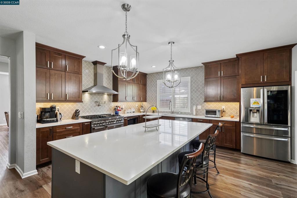 Priced to move quickly don't miss this opportunity. Simply stunning! This 3,770 sq ft residence exudes elegance and style. With 5 bedrooms & 3 baths, it accommodates every lifestyle. The remastered kitchen is a chef's dream, featuring a large center island w quartz counter, a high-end ZLine 7 burner stove, double ovens, a pot-filler, and SS appliances, including refrigerator & dishwasher, plus a corner pantry. The kitchen flows into an inviting family room w/ fireplace and built-in bar w cabinetry and a beverage refrigerator. A wall of windows and slider to the backyard expand entertaining space to outdoors. Conveniently, one bedroom and a full bath are on the ground floor. Plantation shutters throughout. The spacious primary suite offers stunning ridgeline views and dual walk-in closets. The luxurious primary bath has natural light, dual vanities, a soaking tub, and shower. There's ample storage & numerous closets. Unwind on the covered patio in the beautifully landscaped backyard featuring a lush lawn, raised garden bed, platform for hot-tub with ready electrical and a potential pool site. Views: Ridge